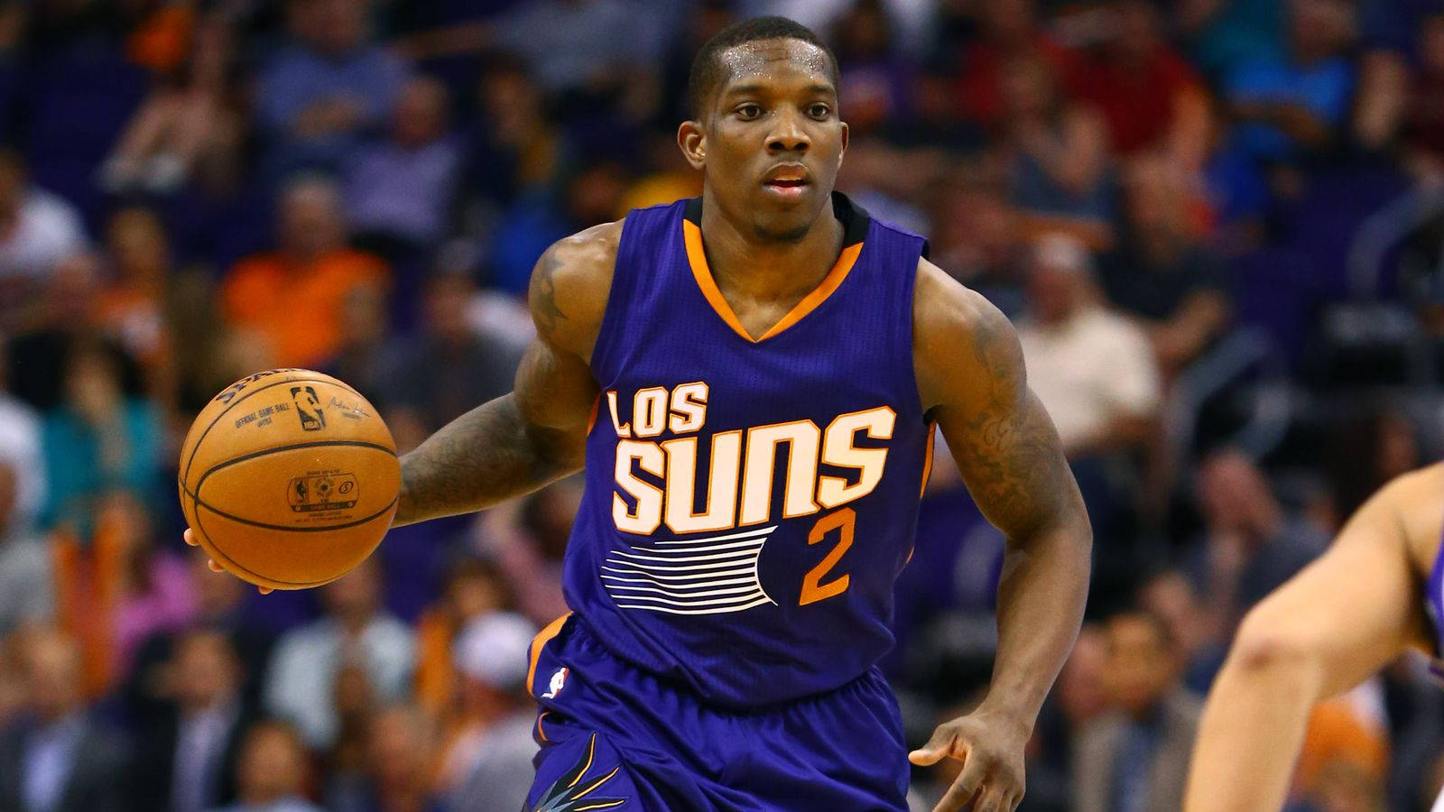 職業NBA球員埃里克·布萊索比賽中策劃戰術 壁紙 — 一位身穿紫色Suns球衣的籃球運動員在激烈的比賽中運球，背景是模糊的人群。
