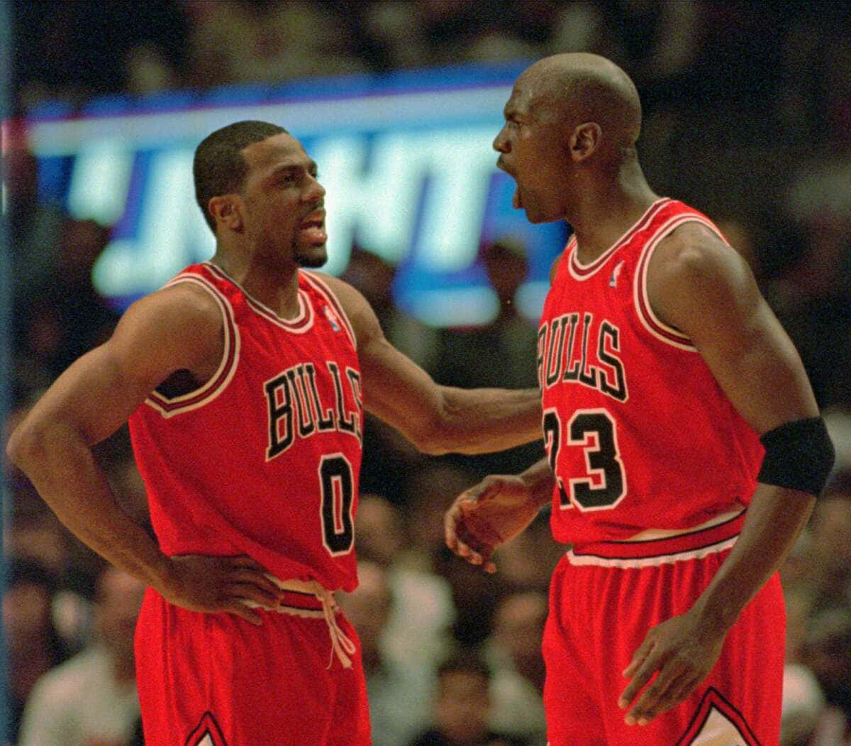 邁克爾·喬丹在傳奇NBA職業生涯中 壁紙 — 兩名身穿紅色球衣的芝加哥公牛隊籃球運動員在明亮的場館燈光下於比賽中激烈交流。