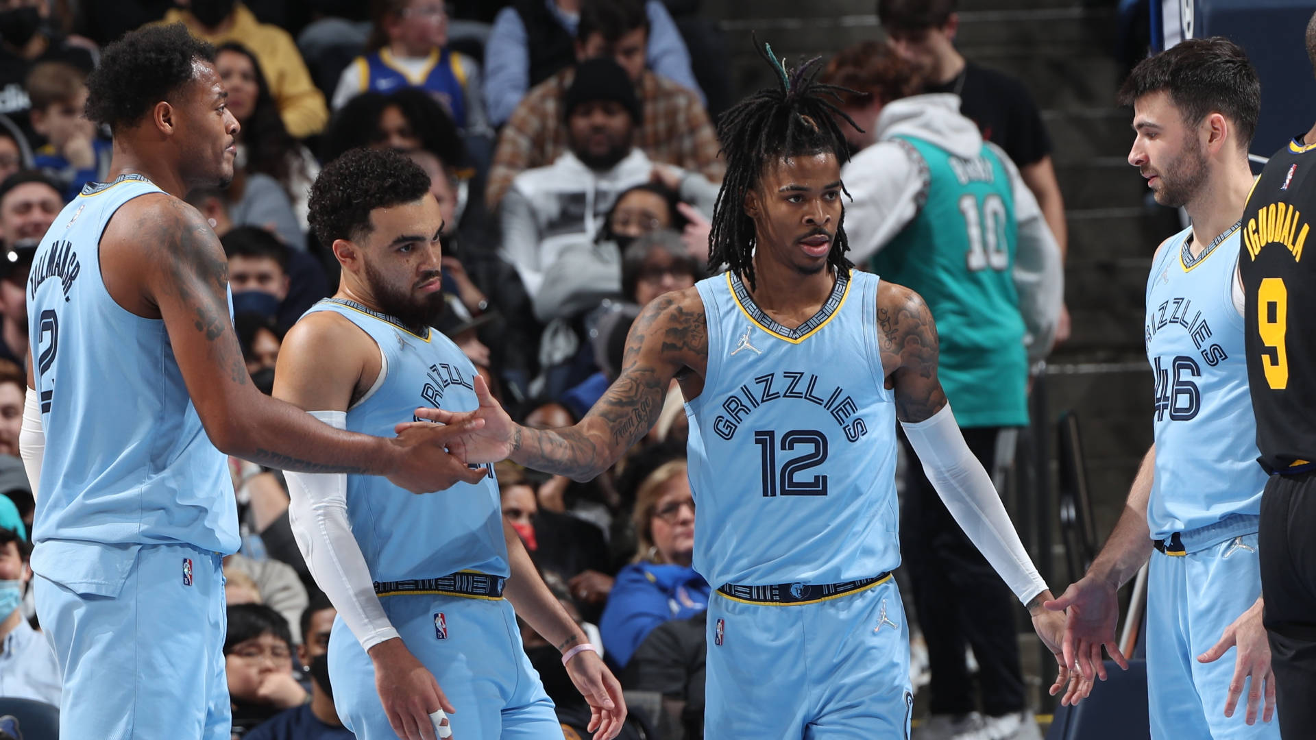 NBA 孟菲斯灰熊隊 壁紙 — 灰熊隊籃球運動員身穿淺藍色球衣在比賽期間於球場上聚集，背景有觀眾。
