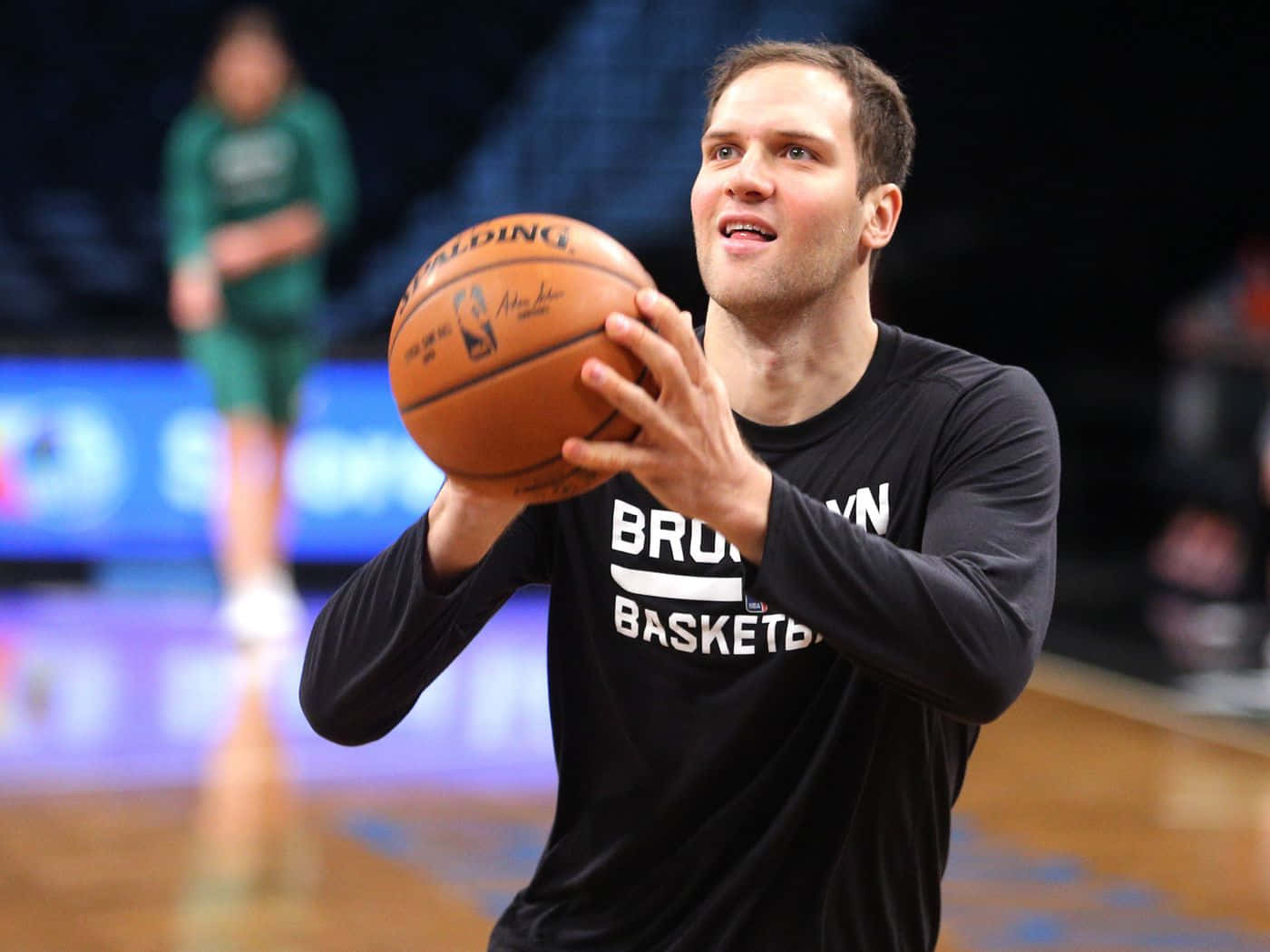 NBA 布魯克林籃網隊 波揚·博格丹諾維奇 壁紙 — 一名身穿黑色布魯克林籃網球衣的籃球運動員，在明亮的場館燈光下，於拋光球場上準備投擲 Spalding 籃球。