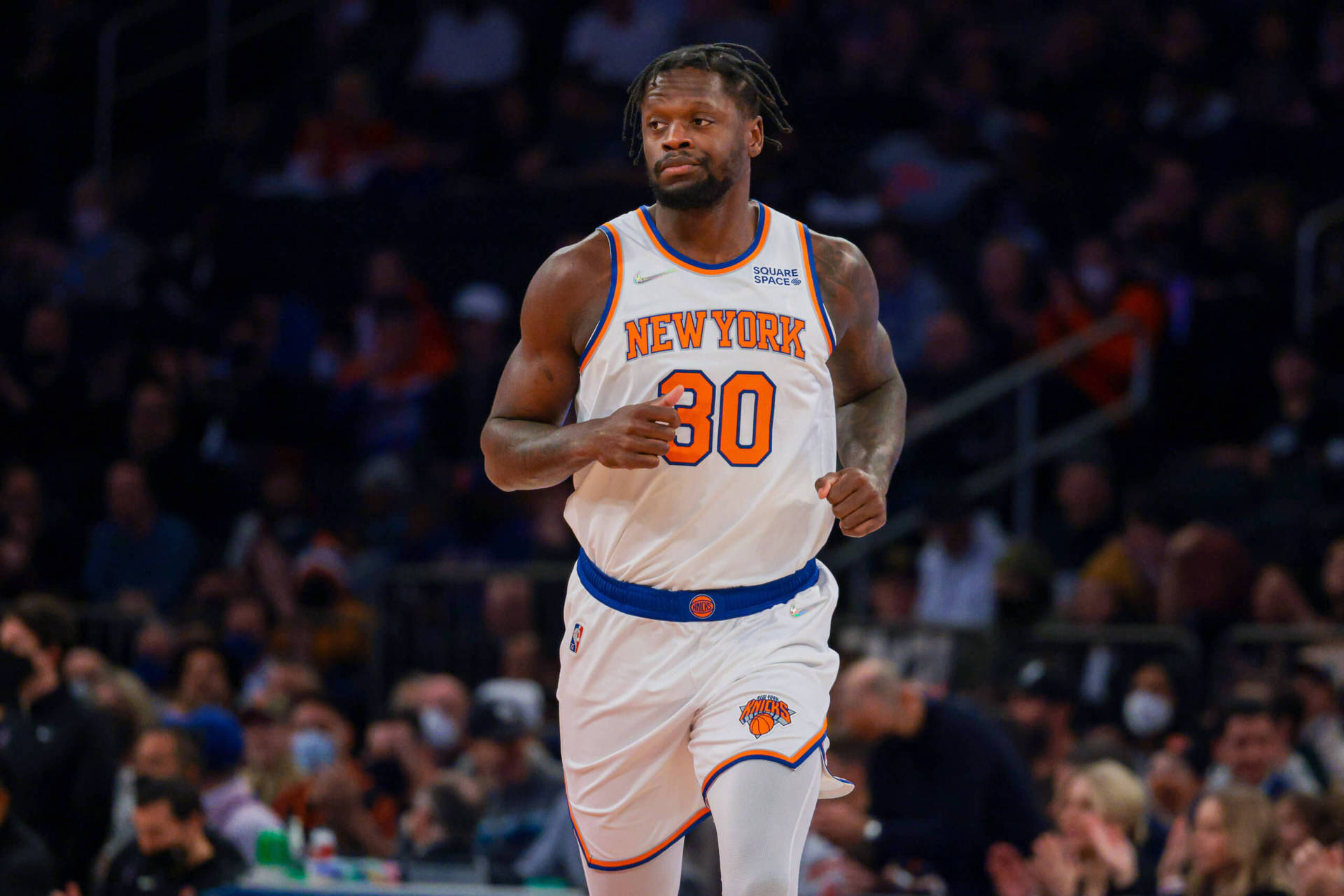 NBA 朱利葉斯·蘭德爾 跑步 壁紙 — 一名身穿紐約人隊球衣的籃球運動員在球場上奔跑，背景是模糊的人群。