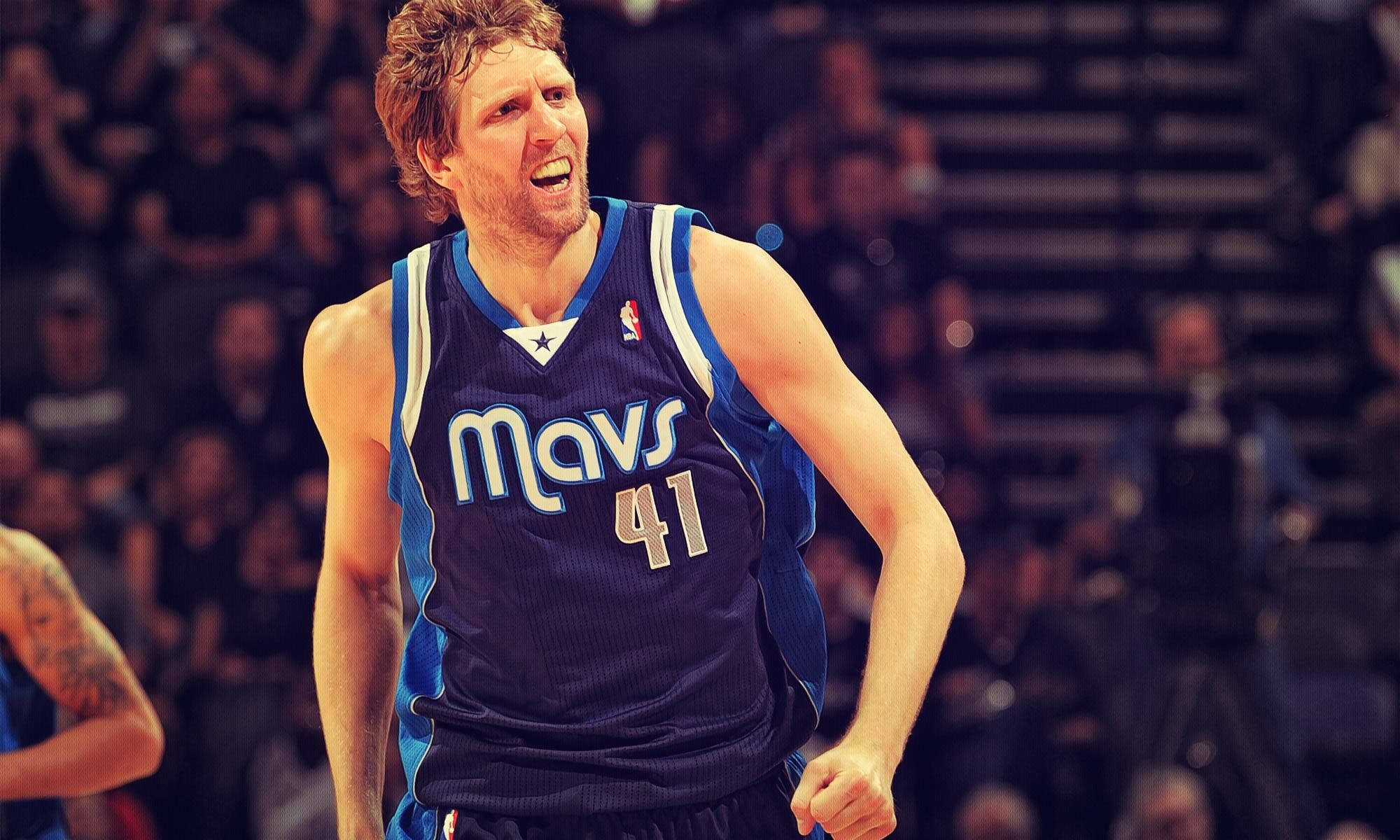 NBA 獨行俠 德克·諾維茨基 壁紙 — 一名身穿藍色Mavs球衣41號的籃球運動員在場館燈光下比賽時激烈咆哮。