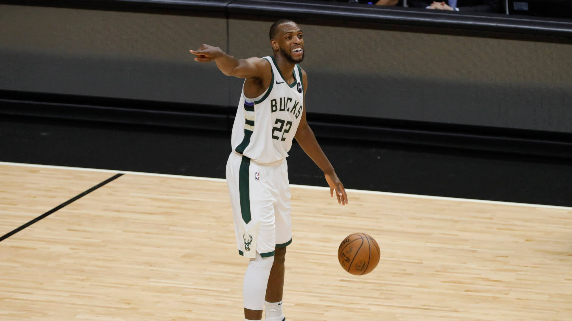 NBA 球員 Khris Middleton 壁紙 — 一名身穿白色和綠色球衣的密爾沃基公鹿籃球運動員在木地板上運球比賽。
