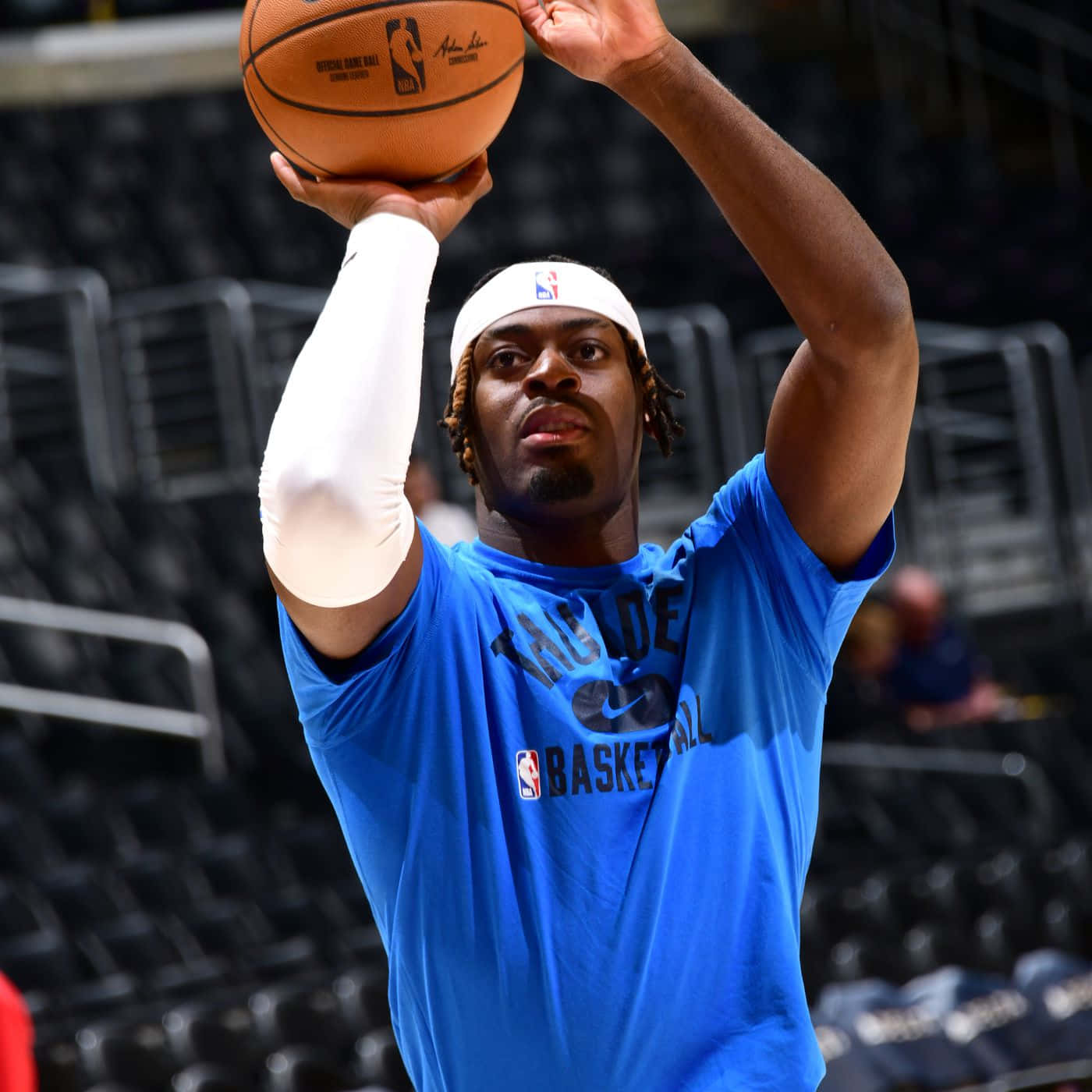 NBA 第5號球衣路文頓·多特 壁紙 — 一名身穿藍色訓練衫的籃球運動員在空蕩蕩的場館中，全神貫注地準備投籃。
