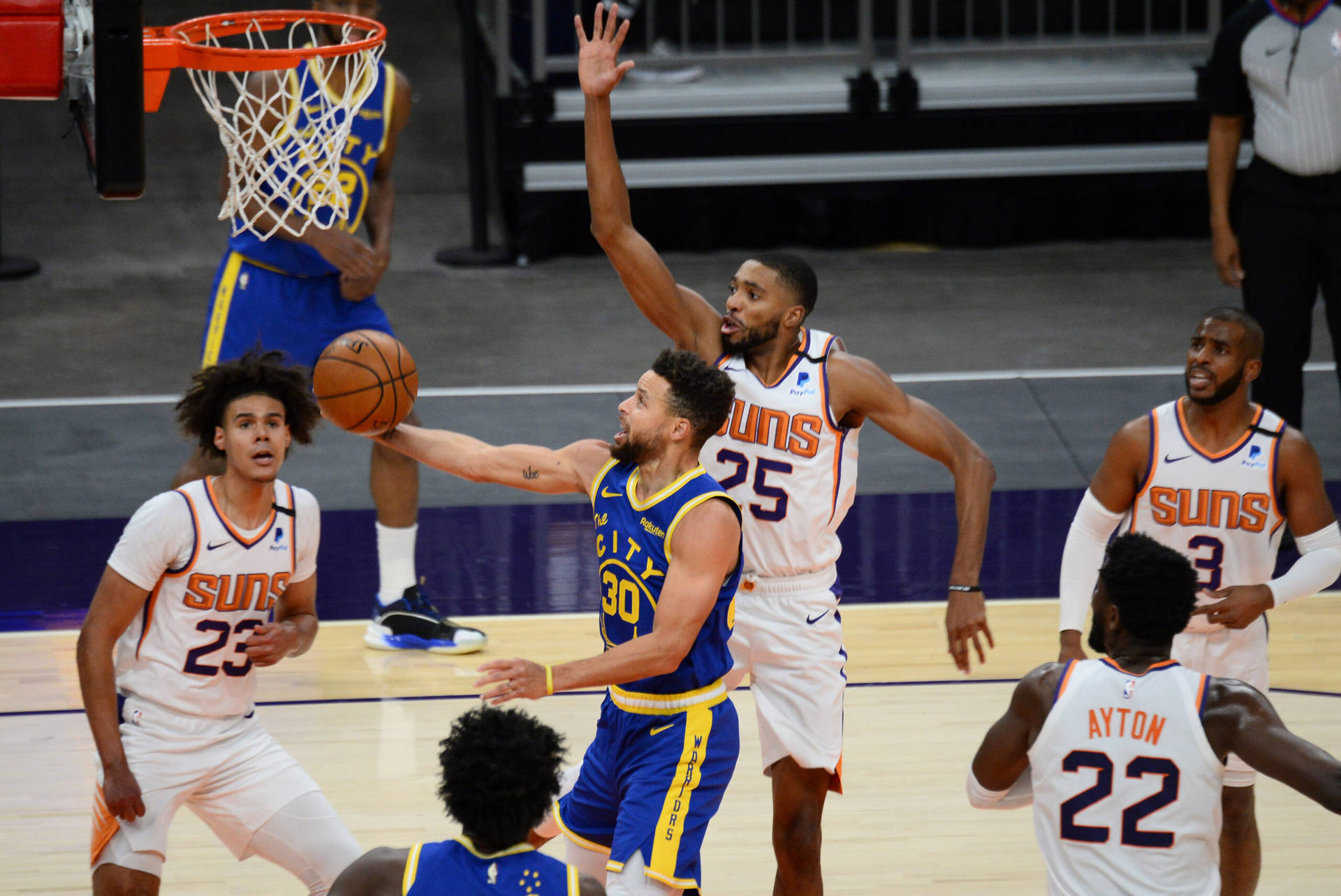 NBA 華盛頓太陽隊 米卡爾·布里奇斯 壁紙 — 一名身穿藍色球衣的籃球運動員在關鍵比賽中帶球上籃，而身穿白色球衣的防守球員則試圖封阻投籃。