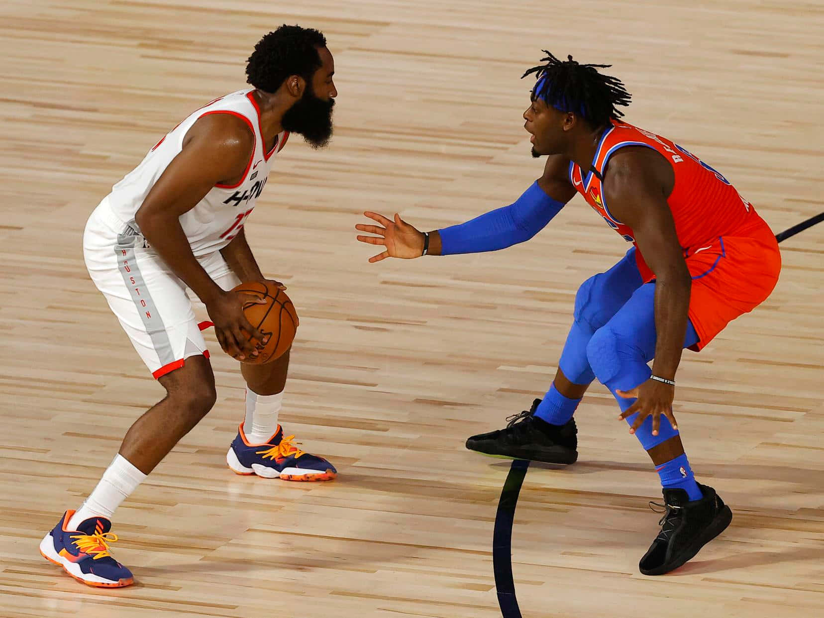 NBA 詹姆斯·哈登與路文頓·多特 壁紙 — 兩名籃球運動員在拋光木地板上激烈競爭，一人運球，另一人積極防守。