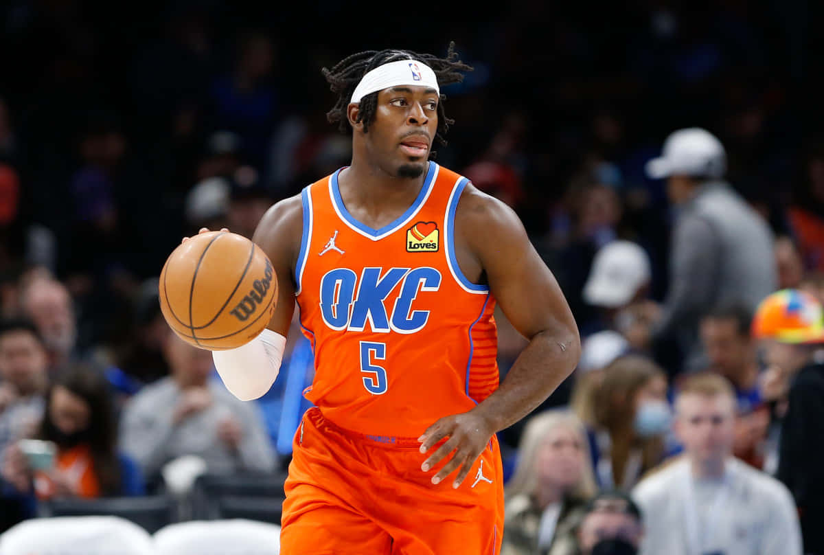 NBA 諾倫·道特 球衣編號5號 壁紙 — 一名身穿橙色OKC球衣的籃球運動員在比賽中運球，背景是模糊的觀眾。