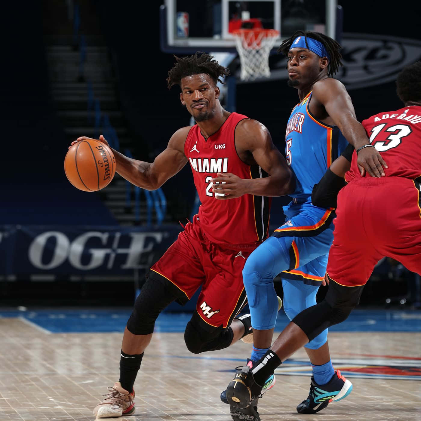 NBA 路文頓·多特防守揚尼斯·阿德托昆博 壁紙 — 一名身穿紅色的邁阿密熱火球員正在運球，同時被一名身穿藍色的奧克拉荷馬城雷霆球員緊密防守，這是一場高風險的籃球比賽。
