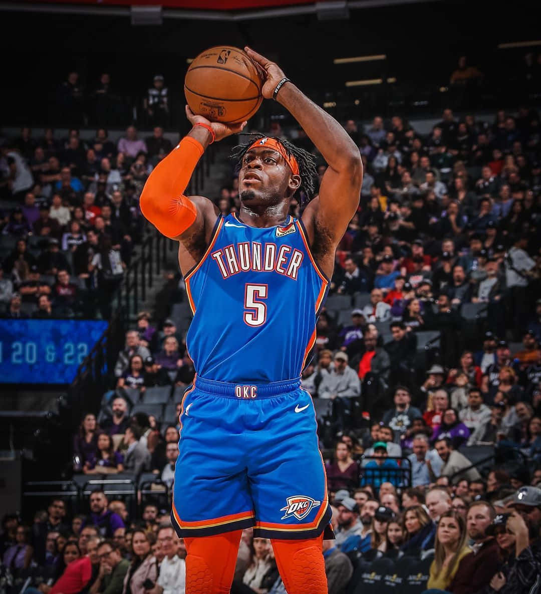 NBA 雷霆隊路文頓·多特三分球 壁紙 — 一名身穿藍色和橙色雷霆球衣的籃球運動員在明亮的燈光下，在擠滿觀眾的體育館中投籃。