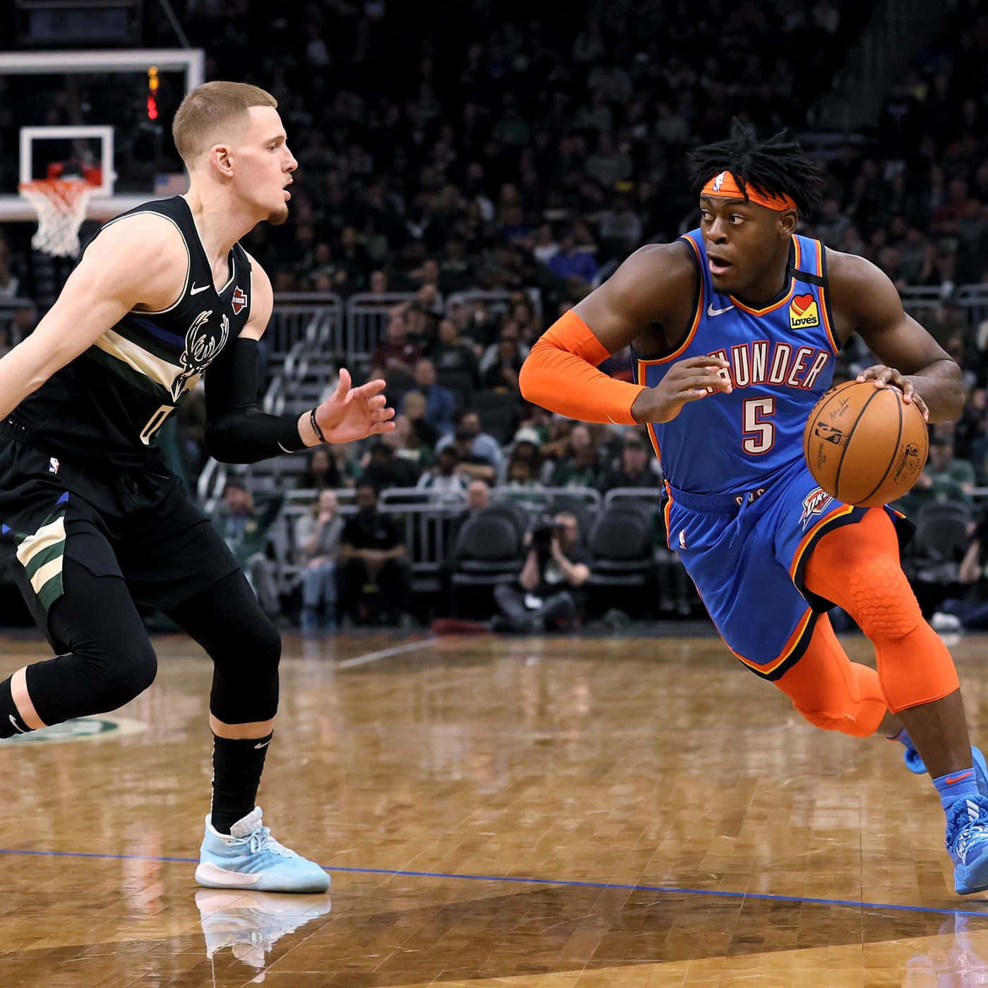NBA 雷霆隊路文頓·多特快攻 壁紙 — 一名身穿藍橙色球衣的籃球運動員在體育館燈光下，於光滑的球場上運球越過一名身穿黑色球衣的防守球員。