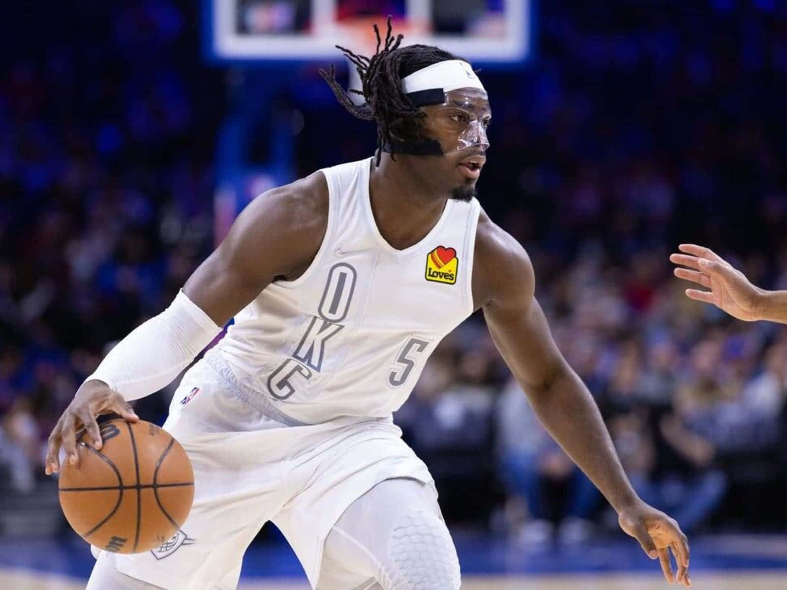 NBA 雷霆隊路文頓·多特戴鼻樑護具 壁紙 — 一名身穿白色OKC球衣的籃球運動員在明亮的場館燈光下於比賽中激烈運球。