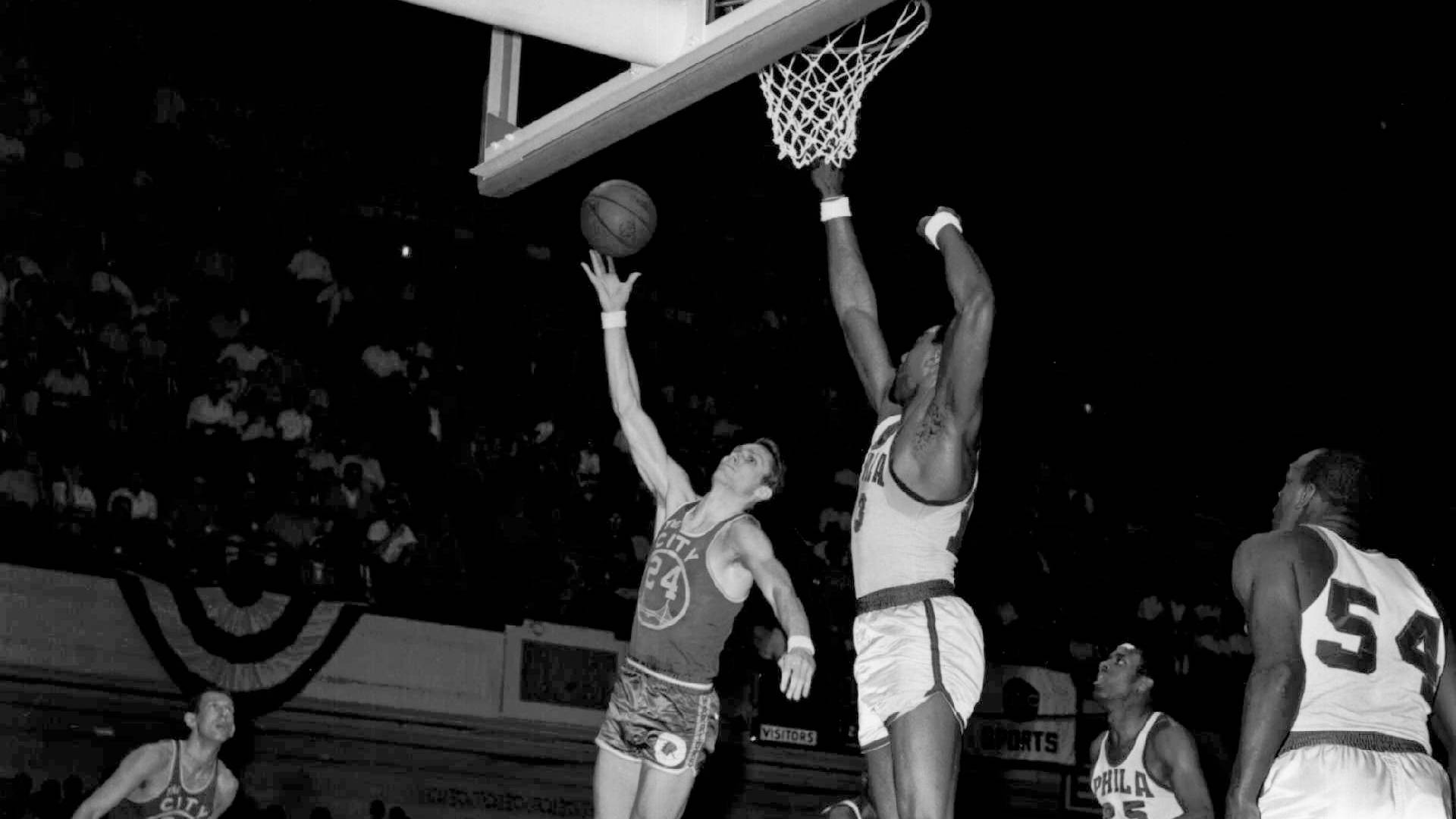 NBA總決賽1962賽事 壁紙 — 黑白動作鏡頭，籃球運動員在明亮的場館燈光下半空中爭奪入樽。