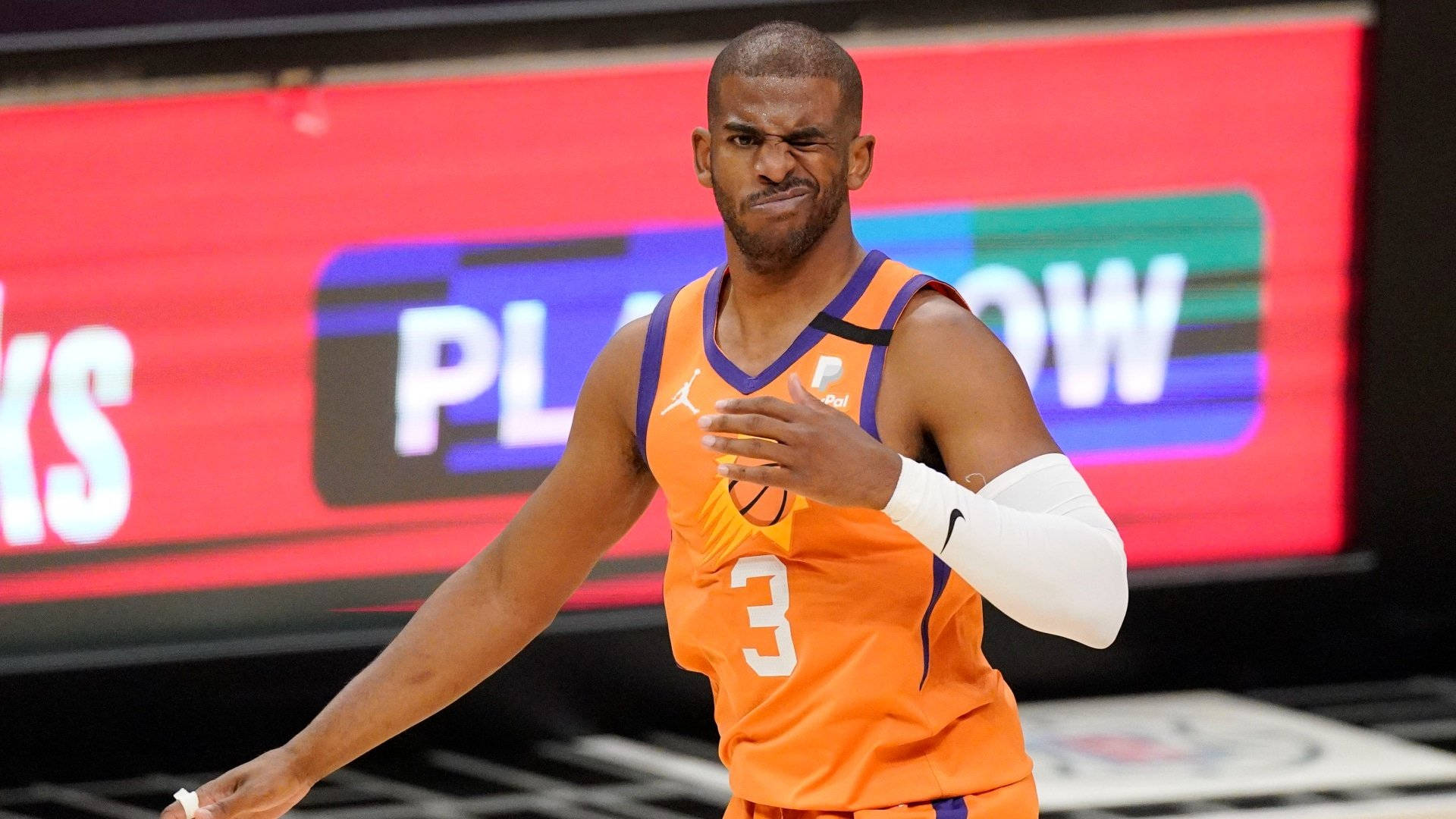 NBA總決賽2021鳳凰城太陽隊 壁紙 — 一名身穿橙色球衣、背號3號的籃球運動員在球場上激烈地做手勢，身後有紅色記分牌。