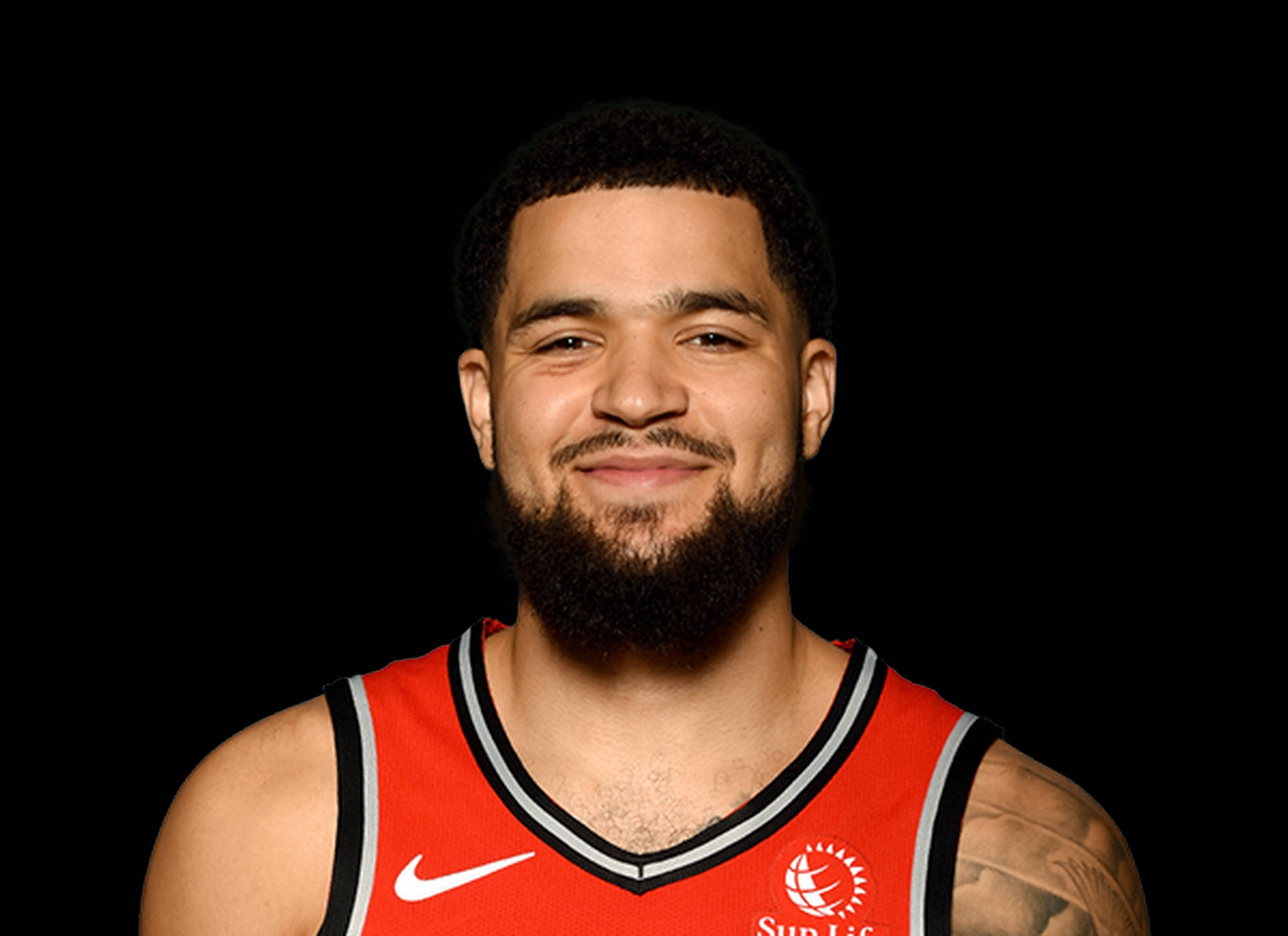 NBA球員Fred VanVleet專業頭像 壁紙 — 一位留鬍子的籃球運動員微笑著，身穿紅色多倫多速龍隊球衣，在黑色背景前擺姿勢。