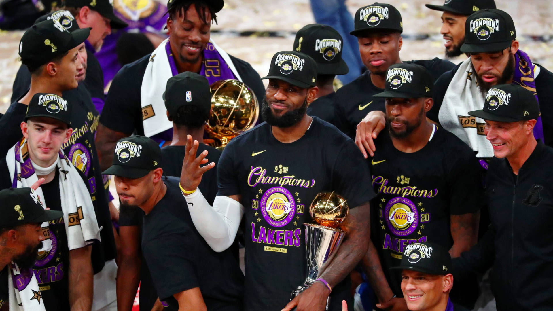 NBA總決賽MVP勒布朗·詹姆斯 壁紙 — 洛杉磯湖人籃球隊戴上黑色「Champions」帽子，手持閃亮的NBA獎盃，慶祝冠軍勝利。