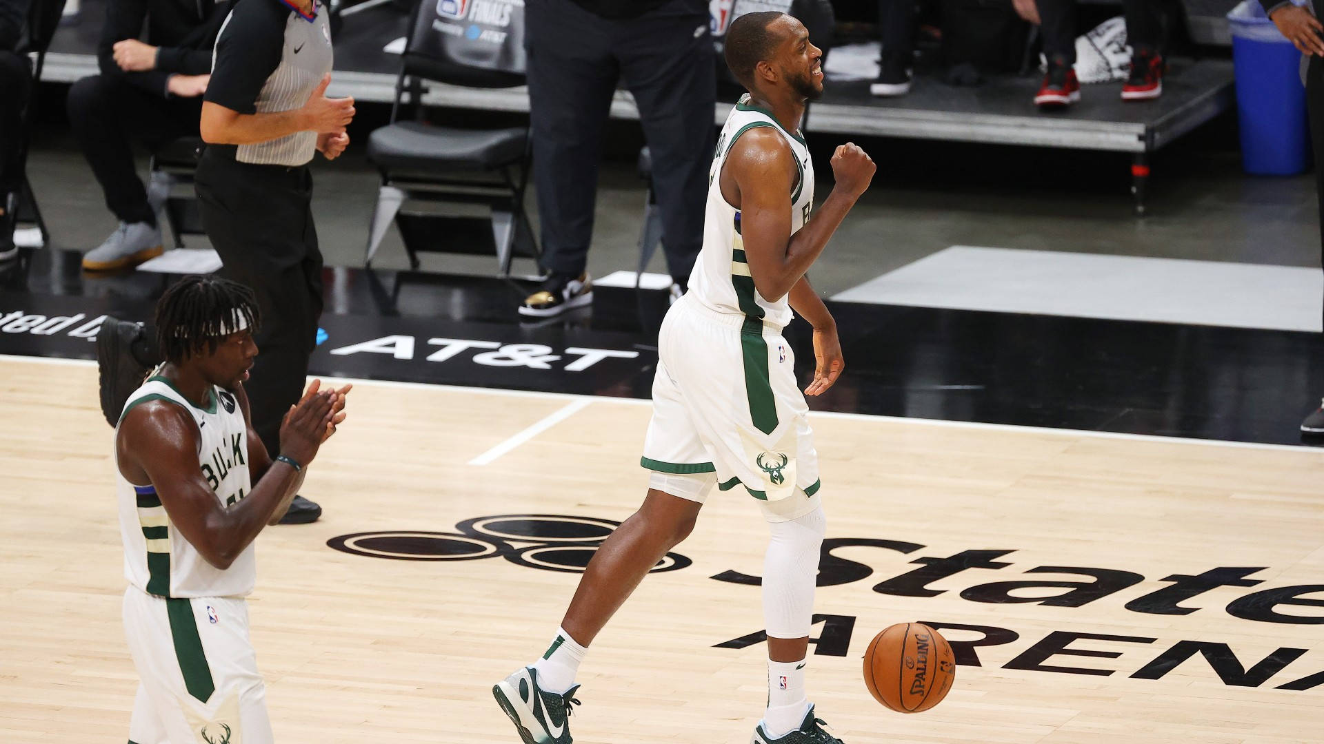 NBA全明星克里斯·米德尔頓 壁紙 — 兩名密爾沃基公鹿籃球運動員在硬木球場上慶祝，附近有一個籃球滾動。