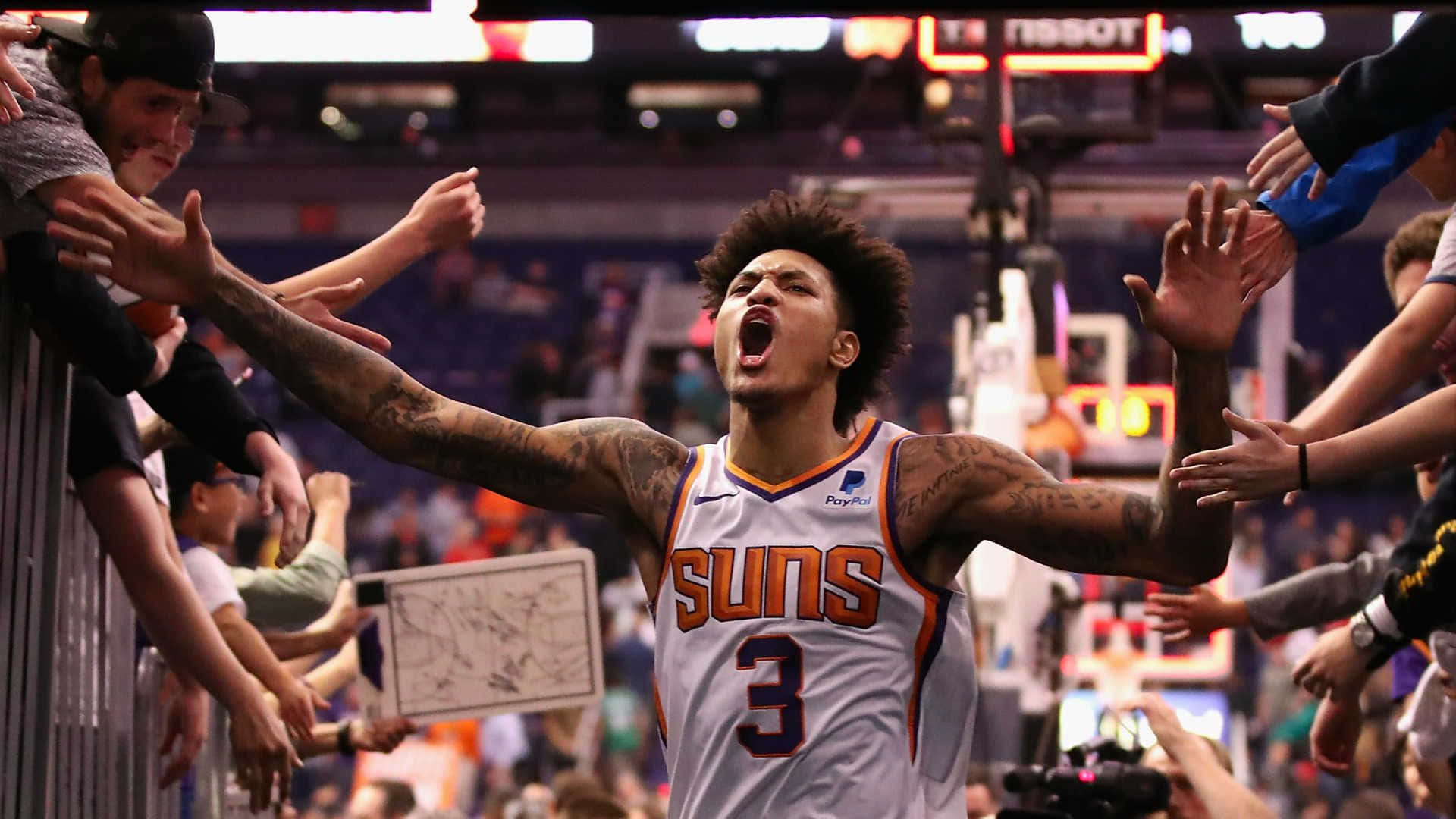 NBA全明星凱利·奧布雷 Jr. 準備投三分球 壁紙 — 鳳凰城太陽隊籃球球員身穿3號球衣，張開雙臂慶祝，球迷越過圍欄與他擊掌。