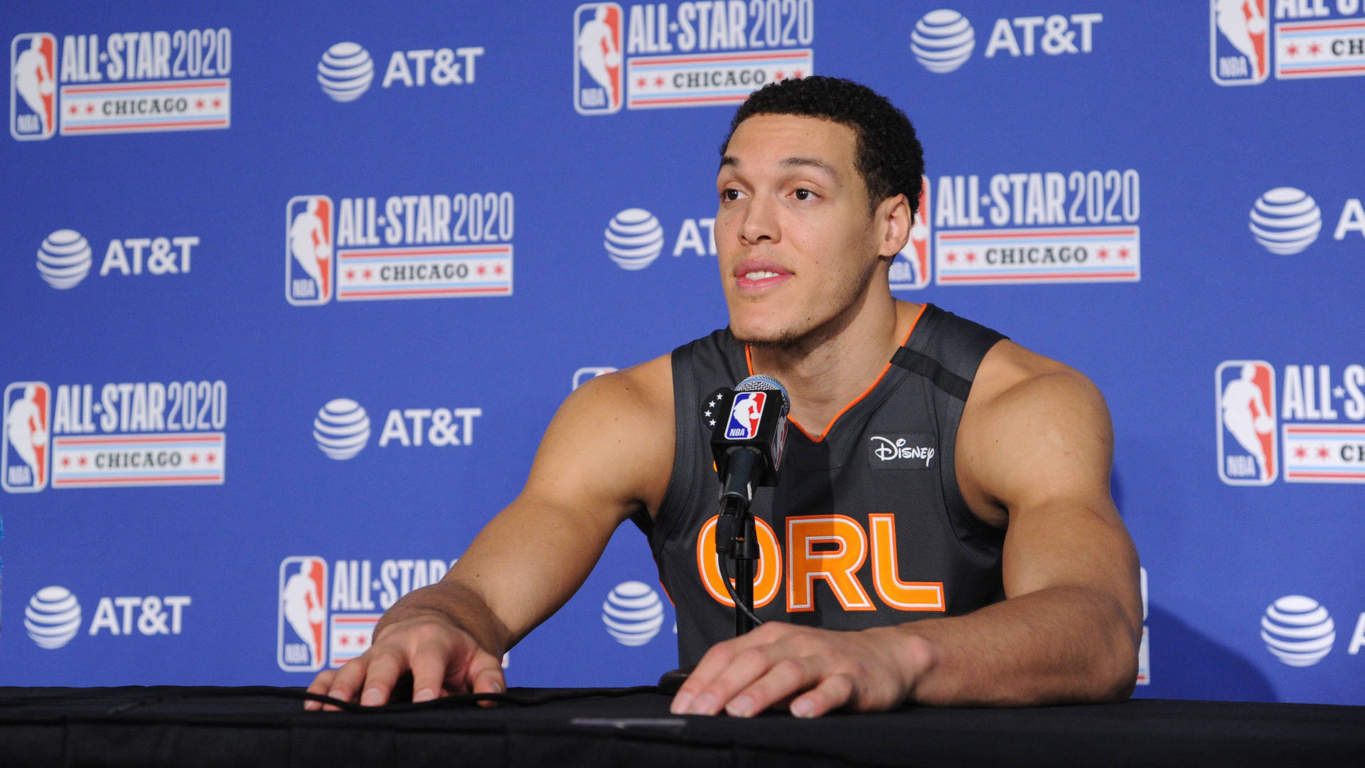 NBA全明星阿隆·戈登比賽中 壁紙 — 籃球運動員在記者會上發言，身穿奧蘭多魔術隊球衣，背景為藍色NBA全明星2020。