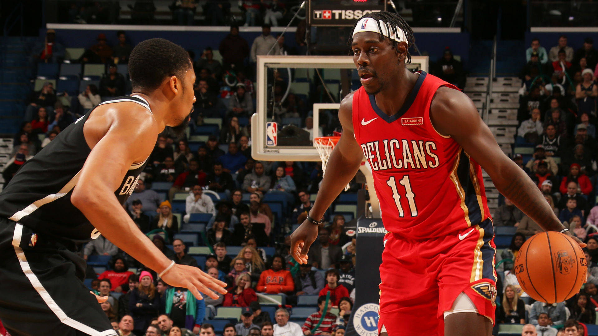NBA冠軍Jrue Holiday 壁紙 — 一名身穿紅色Pelicans球衣的籃球運動員在比賽中運球，同時被一名身穿黑白球衣的對手防守。