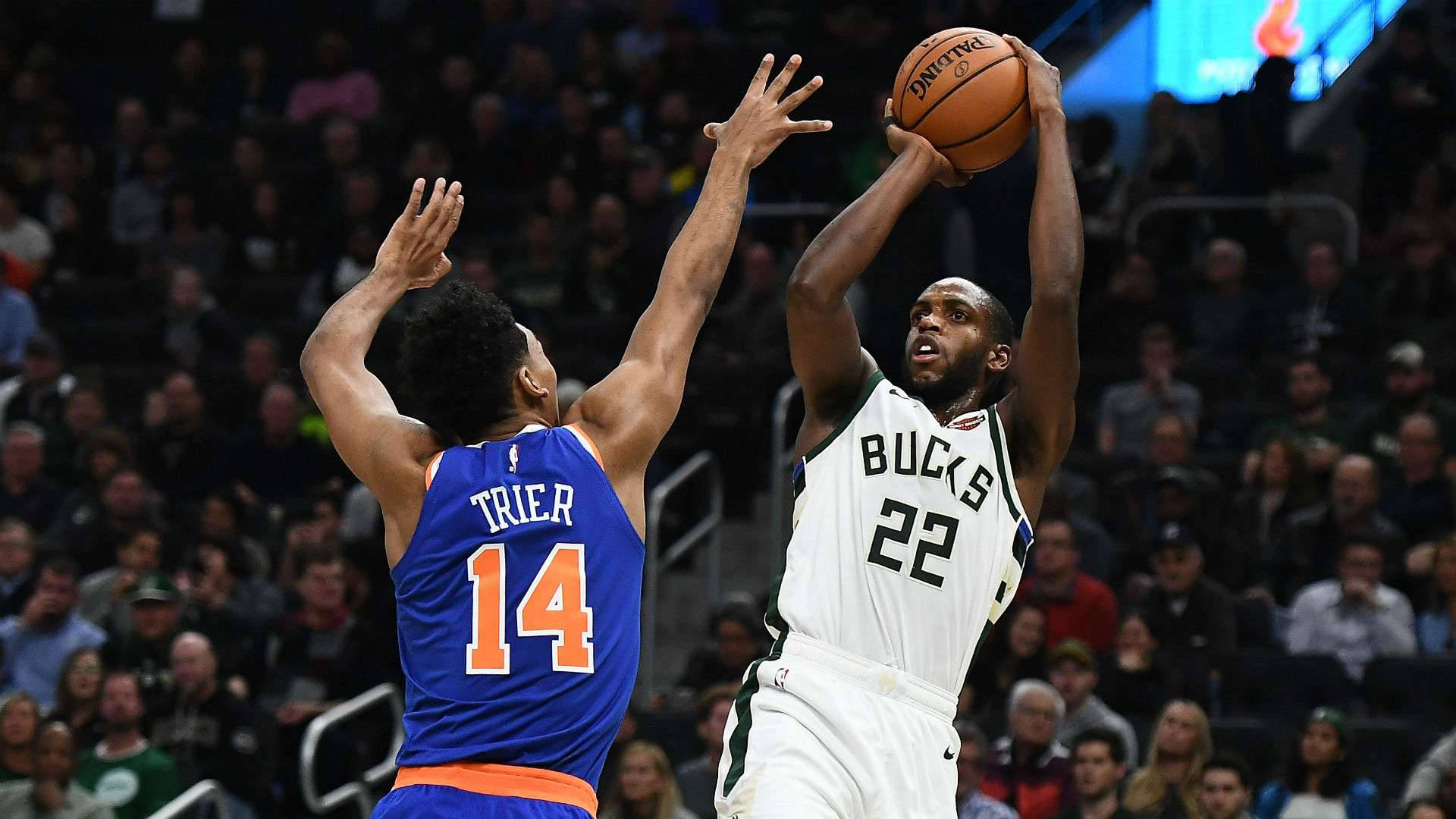 NBA冠軍克里夫·米德頓 壁紙 — 一位身穿白色22號球衣的密爾沃基公鹿球員跳起投籃，而一位身穿藍色14號球衣的紐約人防守球員跳起封阻。