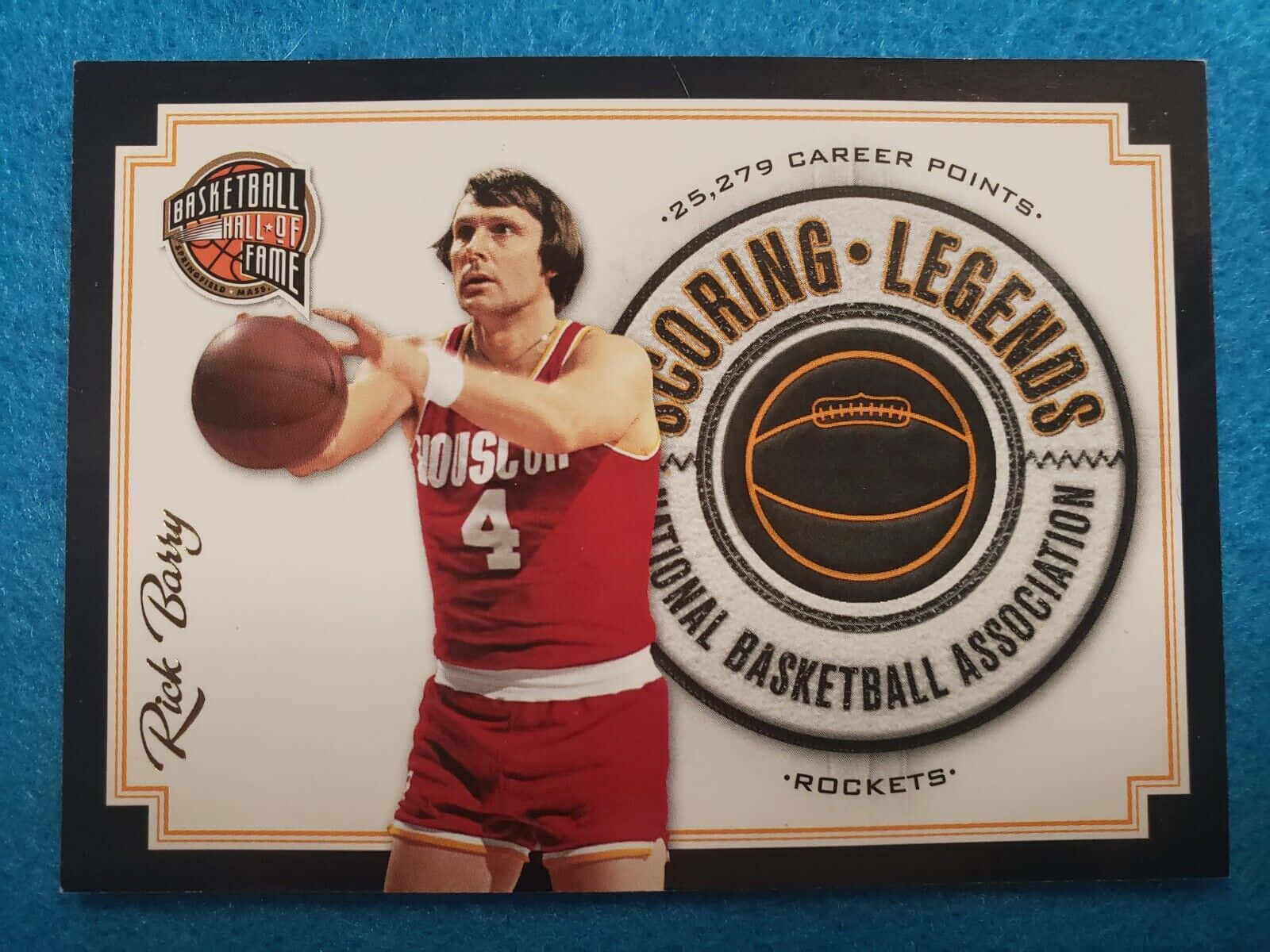 NBA名人堂瑞克·巴里 壁紙 — 身穿紅色侯斯頓火箭隊球衣的Rick Barry，在藍色紋理背景前，準備在一張復古名人堂交易卡上投籃。
