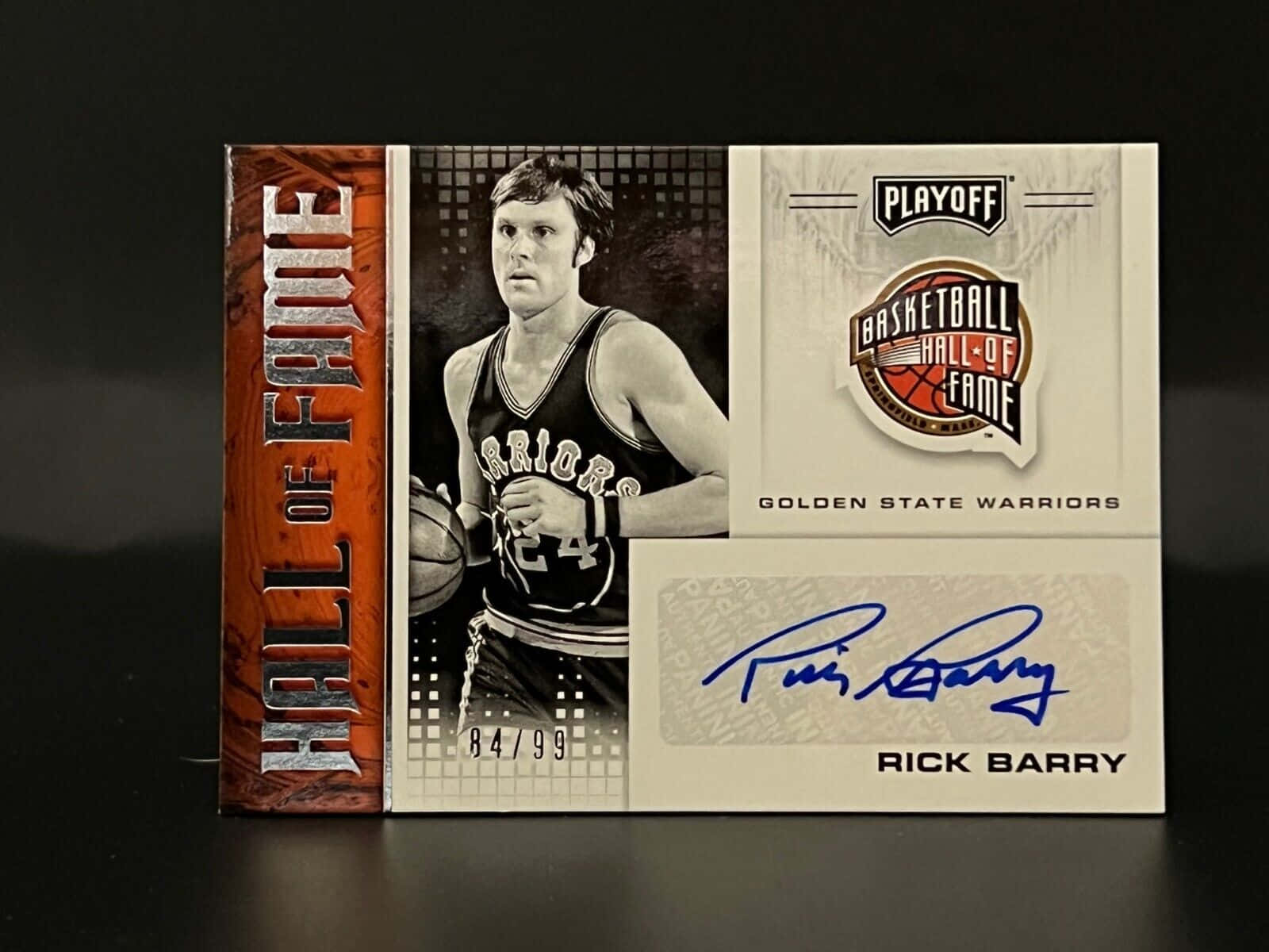 NBA名人堂瑞克·巴里卡 壁紙 — 一張籃球交易卡，展示身穿黑色球衣的Rick Barry手持籃球，上面有他的簽名和名人堂標誌，背景為深色。