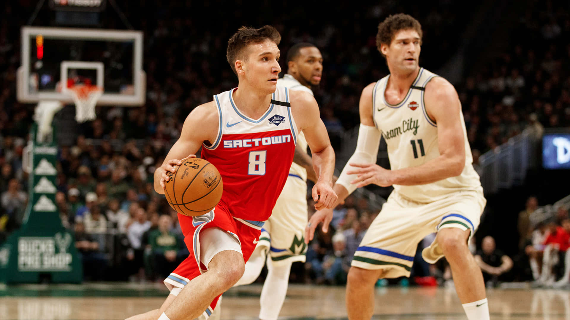 NBA對博格丹·博格丹諾維奇的處罰 壁紙 — 一名身穿紅色 'Sactown' 球衣的籃球運動員在擠滿觀眾的場館中運球，同時被對手防守。