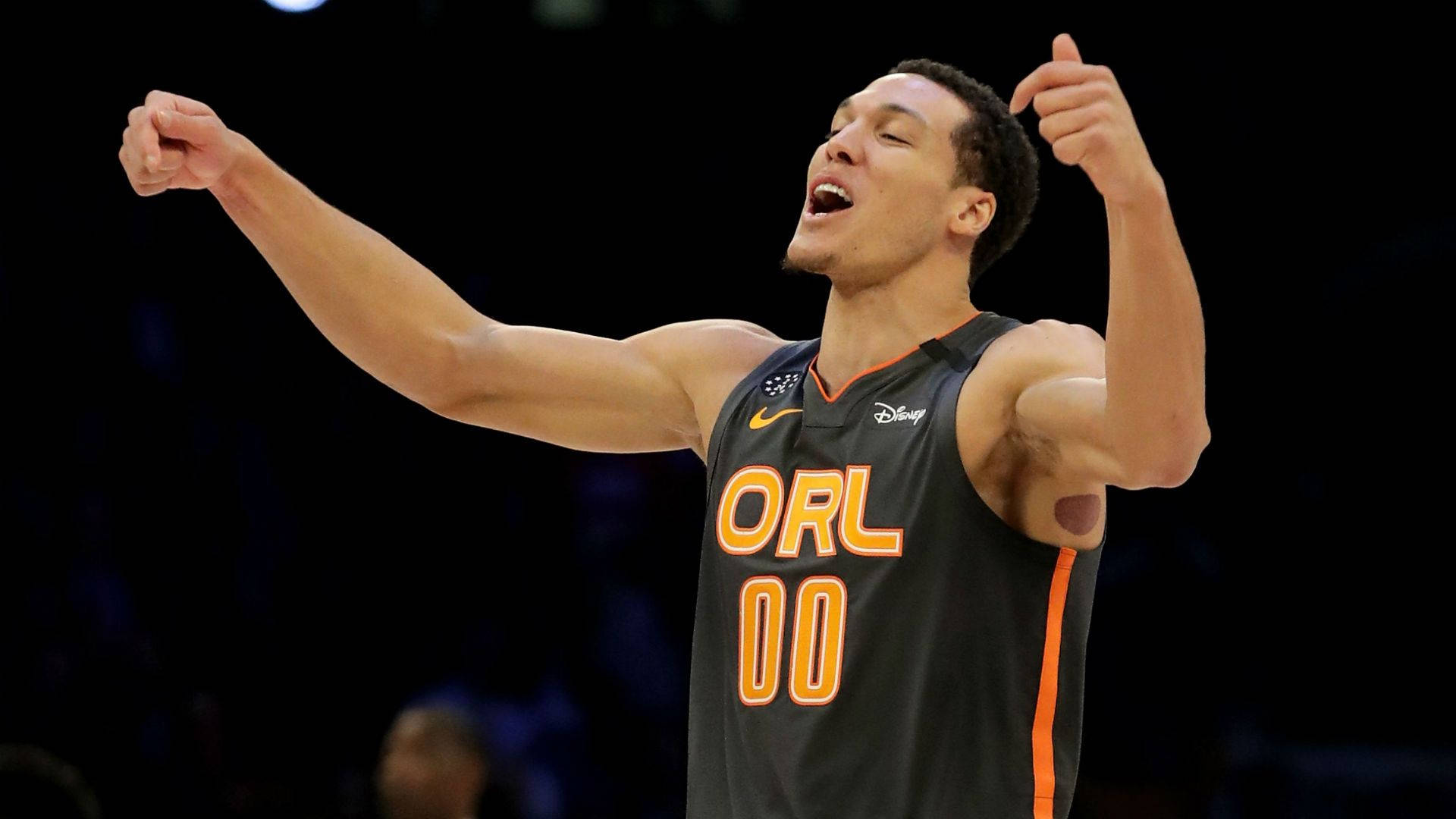 NBA明星阿隆·戈登 壁紙 — 一名身穿奧蘭多球衣的籃球運動員在燈光明亮的場館中高舉雙臂、張開嘴巴，勝利地慶祝。