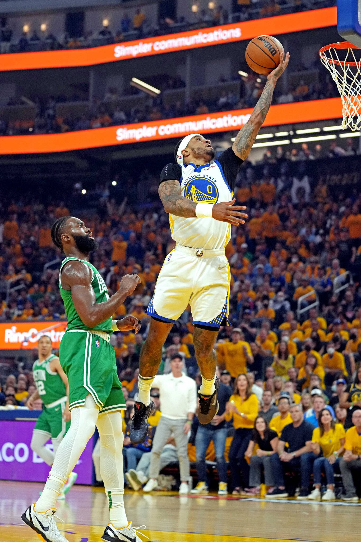 NBA比賽加里·佩頓二世 壁紙 — 一名身穿金色球衣的籃球運動員高高躍起準備入樽，而身穿綠色球衣的防守球員在明亮的場館燈光下專注地注視著。