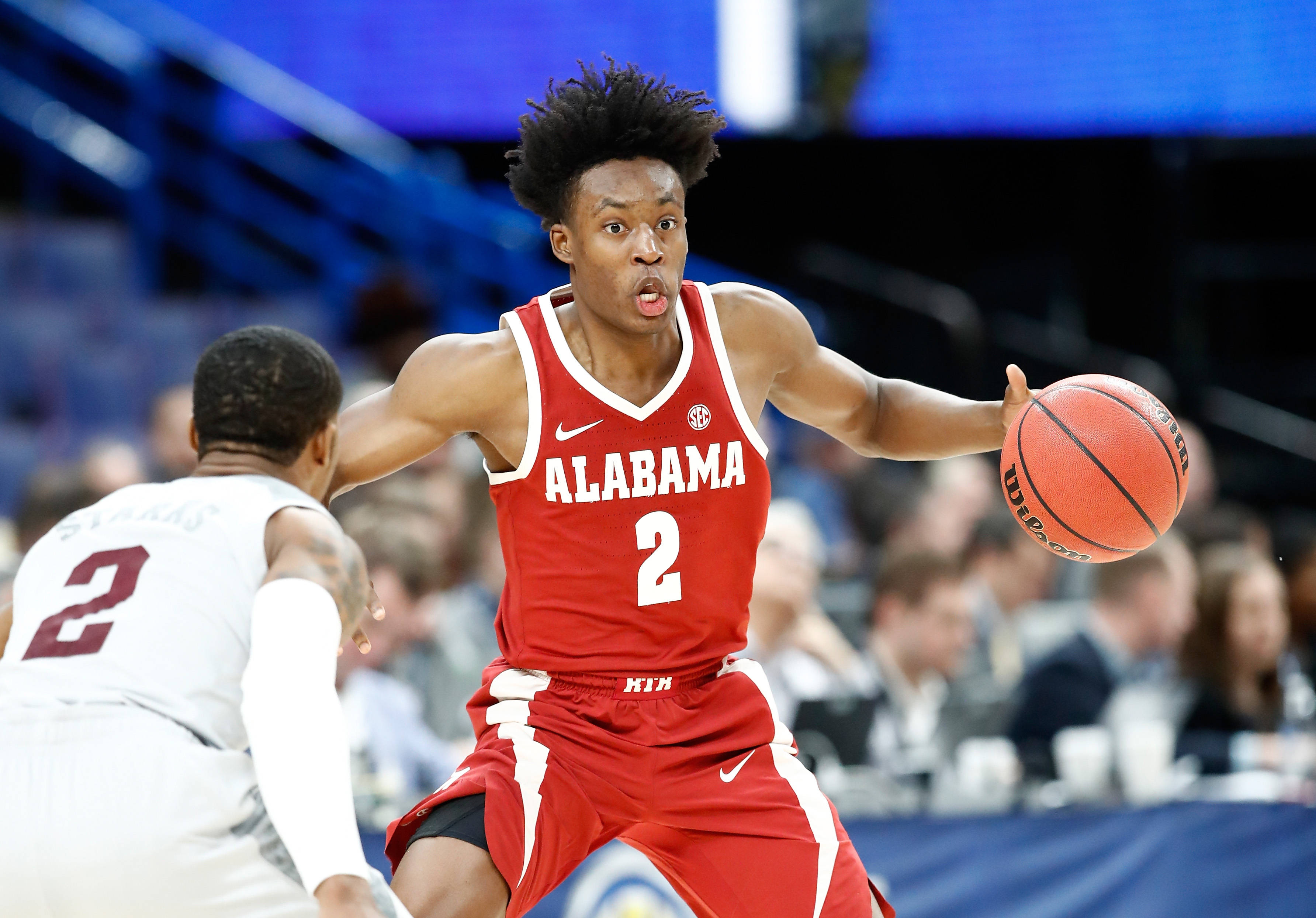 NBA比賽科林·塞克森 壁紙 — 一位專注的阿拉巴馬大學籃球運動員身穿紅色球衣，在明亮的場館中運球，同時被防守。