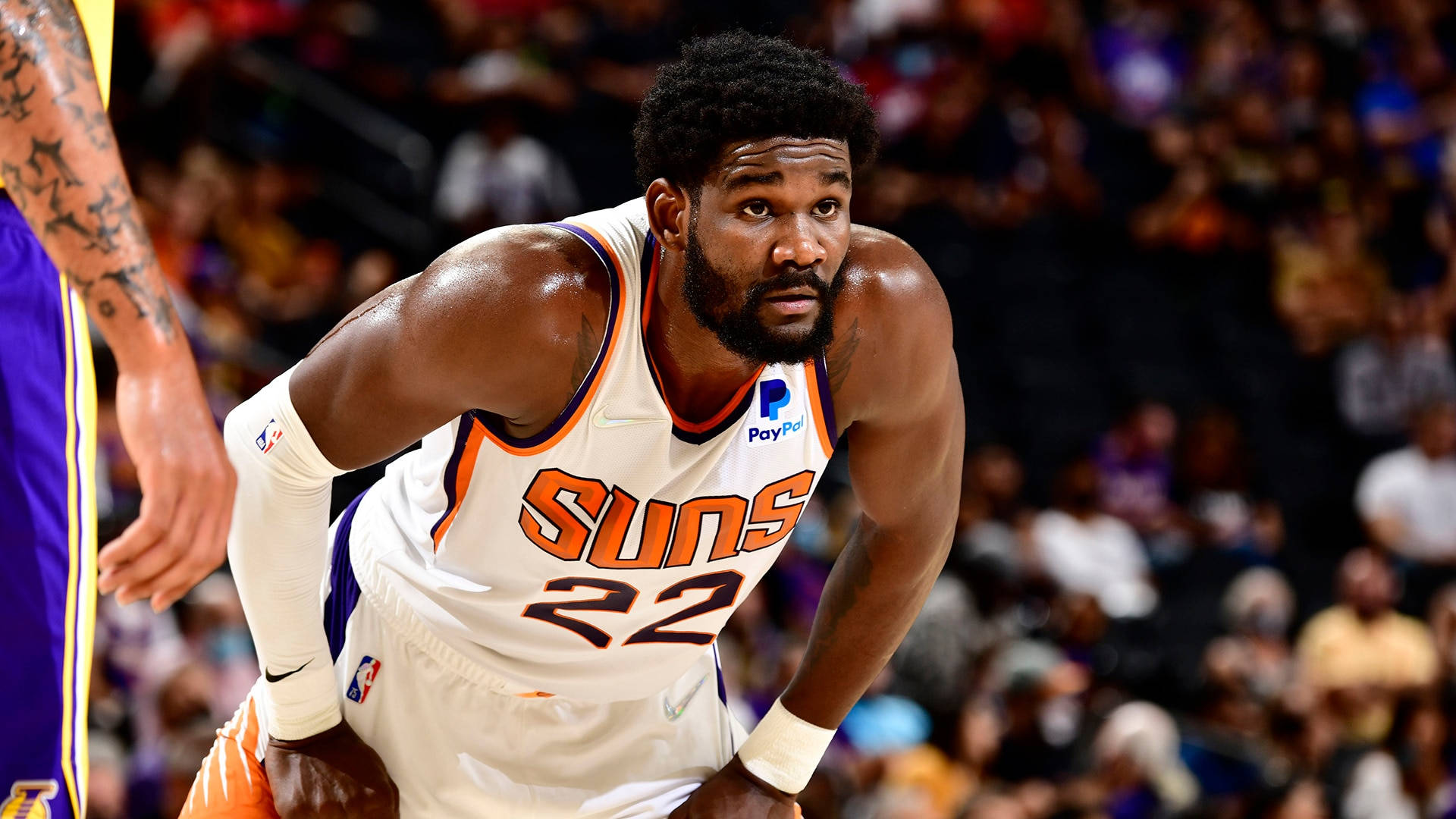 NBA比賽鳳凰城太陽隊德安德烈·艾頓 壁紙 — 一位專注的鳳凰城太陽隊籃球運動員，身穿白色22號球衣，在比賽中於場館燈光下激烈地蹲伏。