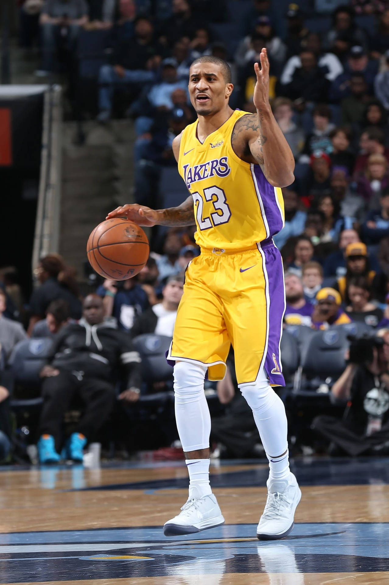NBA湖人隊加里·佩頓二世 壁紙 — 一名身穿黃色湖人隊球衣的籃球運動員在激烈的比賽中運球，背景有觀眾。