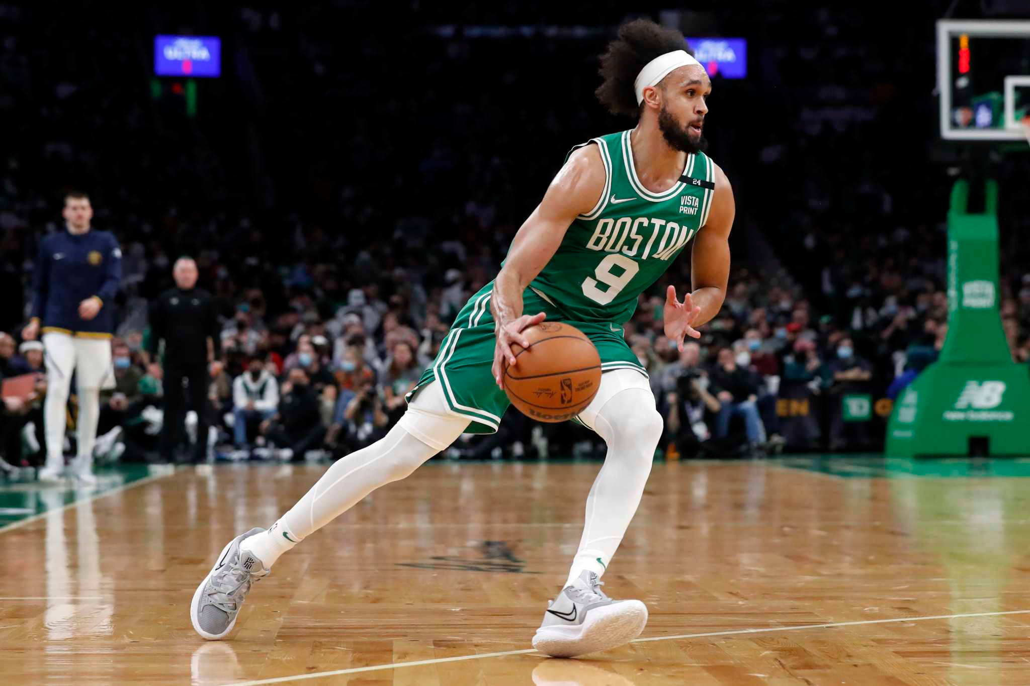 NBA球員德里克·懷特 壁紙 — 一名身穿綠色球衣的波士頓塞爾特人球員在座無虛席的場館比賽中，專注地運球。