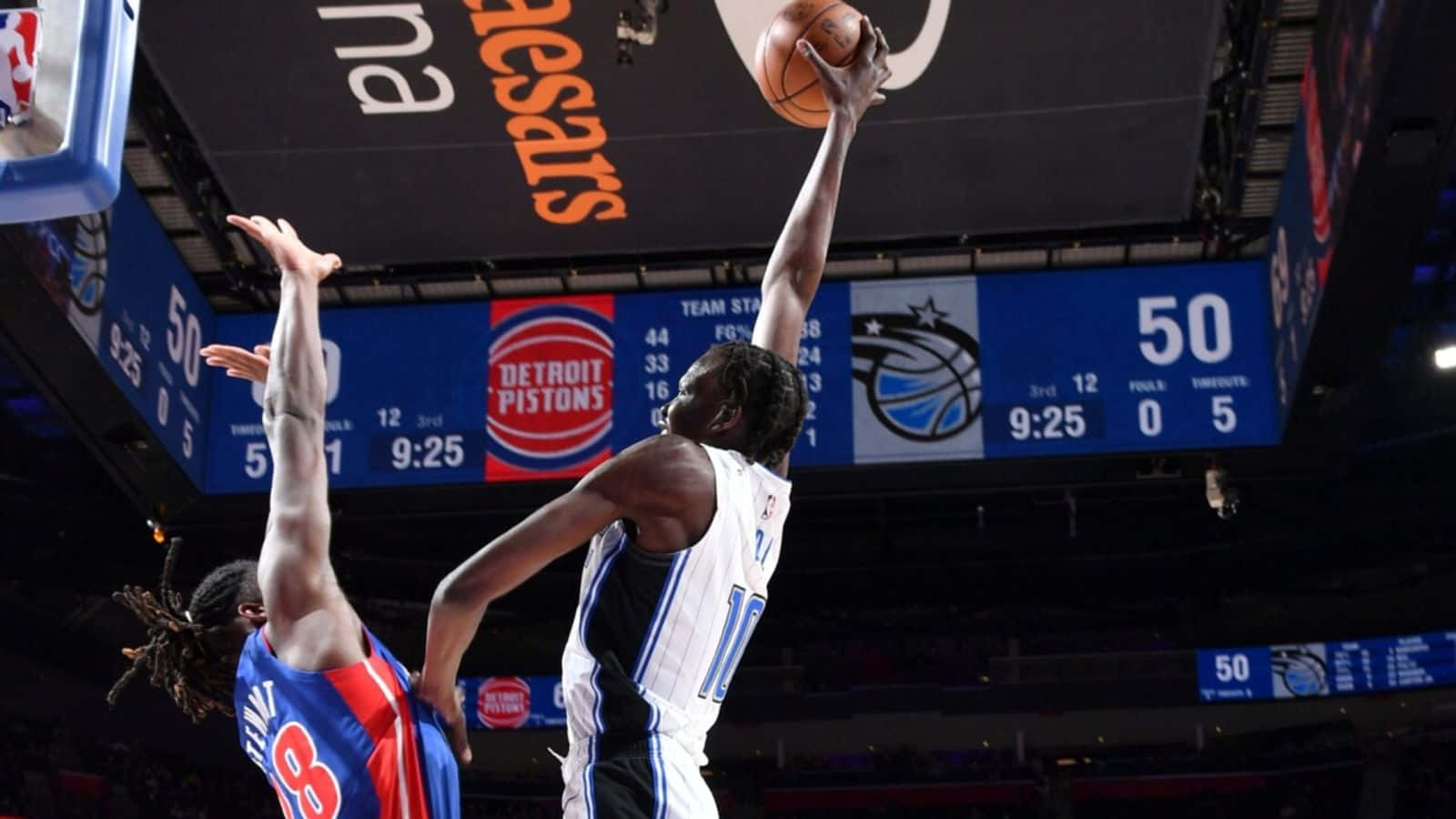 NBA球員盧根茲·多特灌籃 壁紙 — 一名身穿白色球衣的籃球運動員在場館燈光下激烈的比賽中高高躍起，越過藍色球衣的防守球員投籃。
