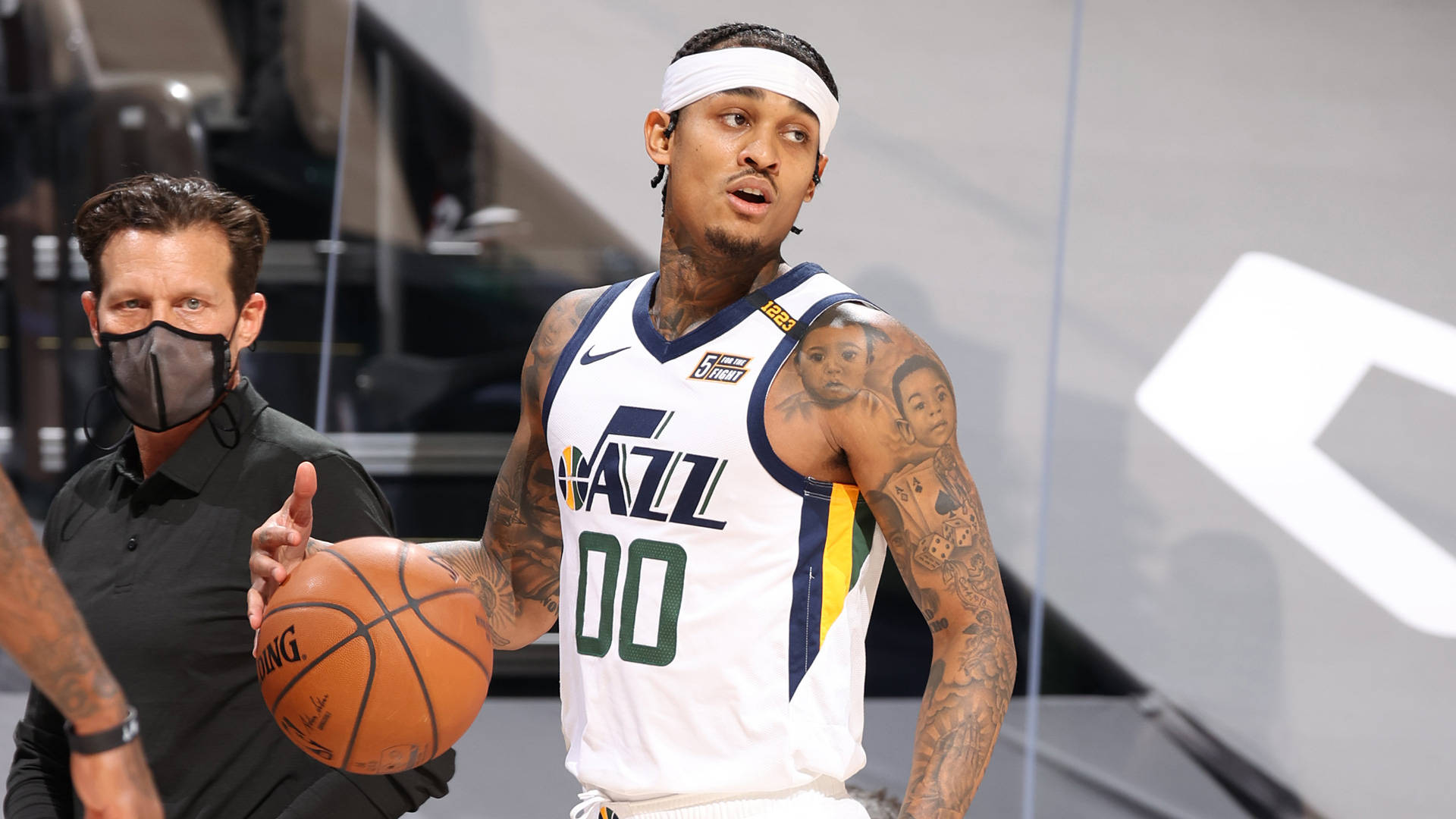 NBA球員約翰·克拉克森 壁紙 — 一名身穿白色爵士隊球衣、背號00的籃球運動員持球，一名戴面具的裁判站在球場附近。
