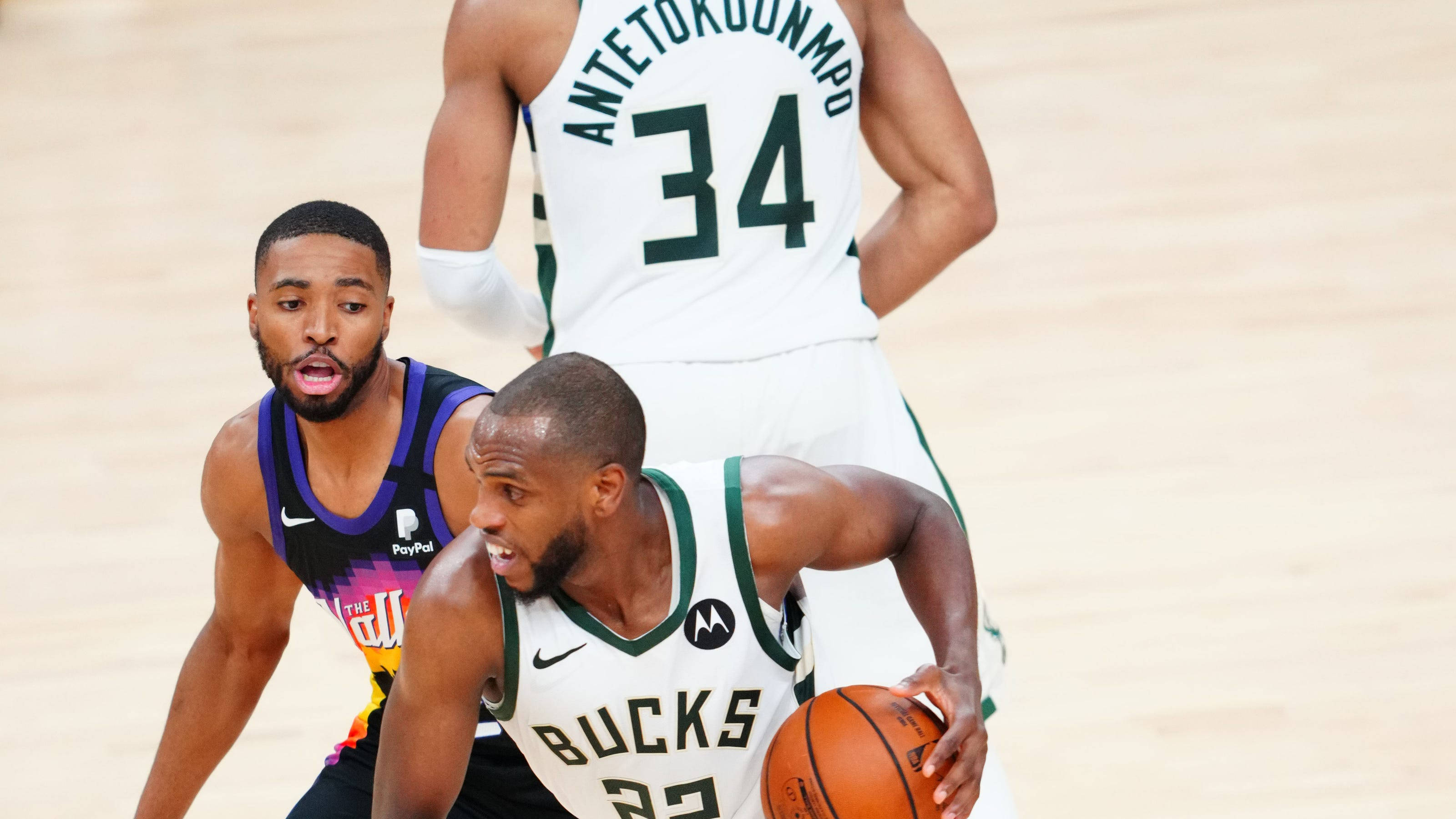 NBA球星克里·米德尔頓 壁紙 — 身穿白色公鹿隊球衣的籃球運動員在激烈的比賽中運球，同時被身穿紫色球衣的對手防守。