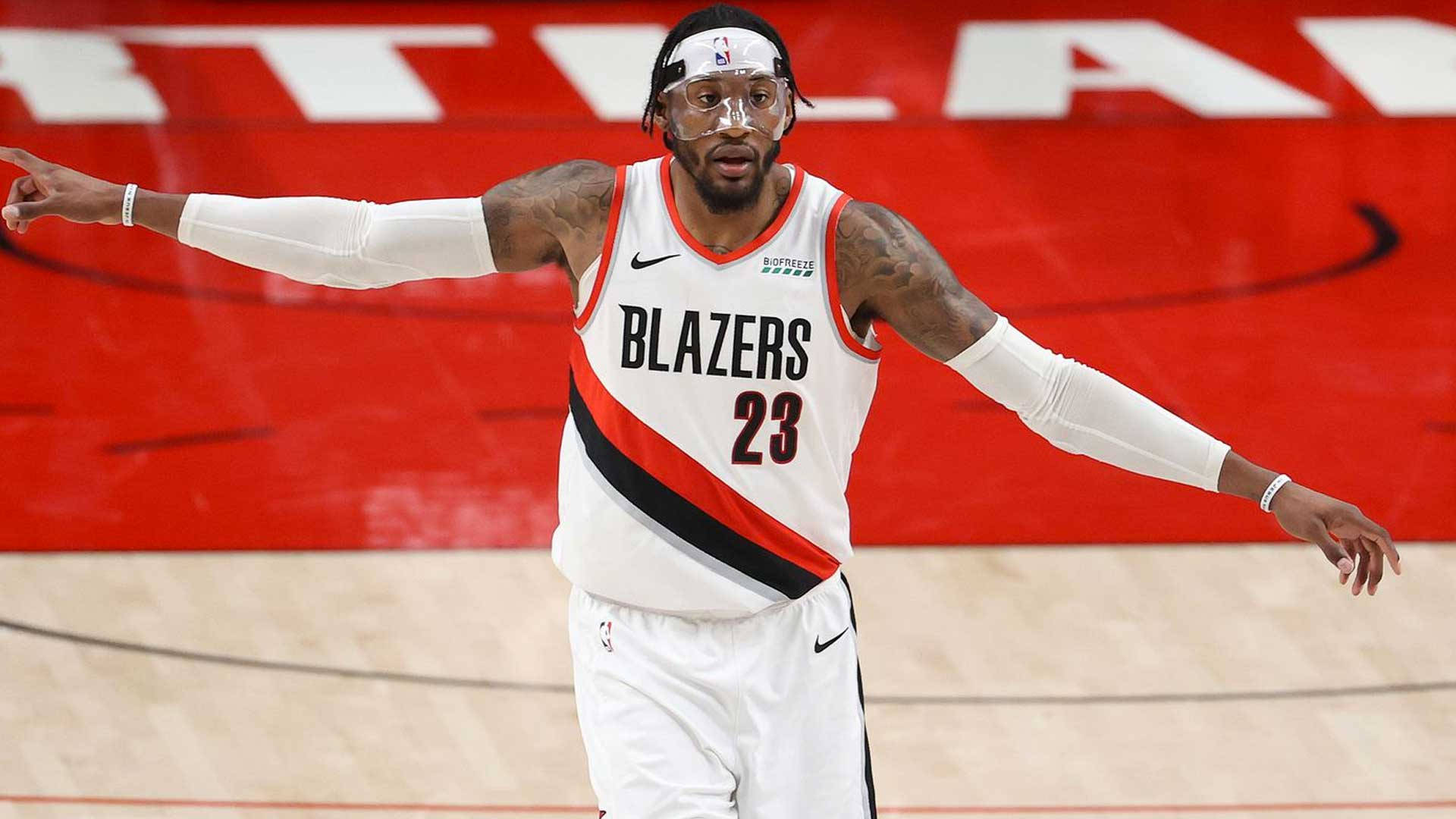 NBA球星羅伯特·科維頓賽場瞬間 壁紙 — 一名身穿白色 Blazers 球衣、號碼 23 的籃球運動員在紅色背景的球場上激動地做手勢。