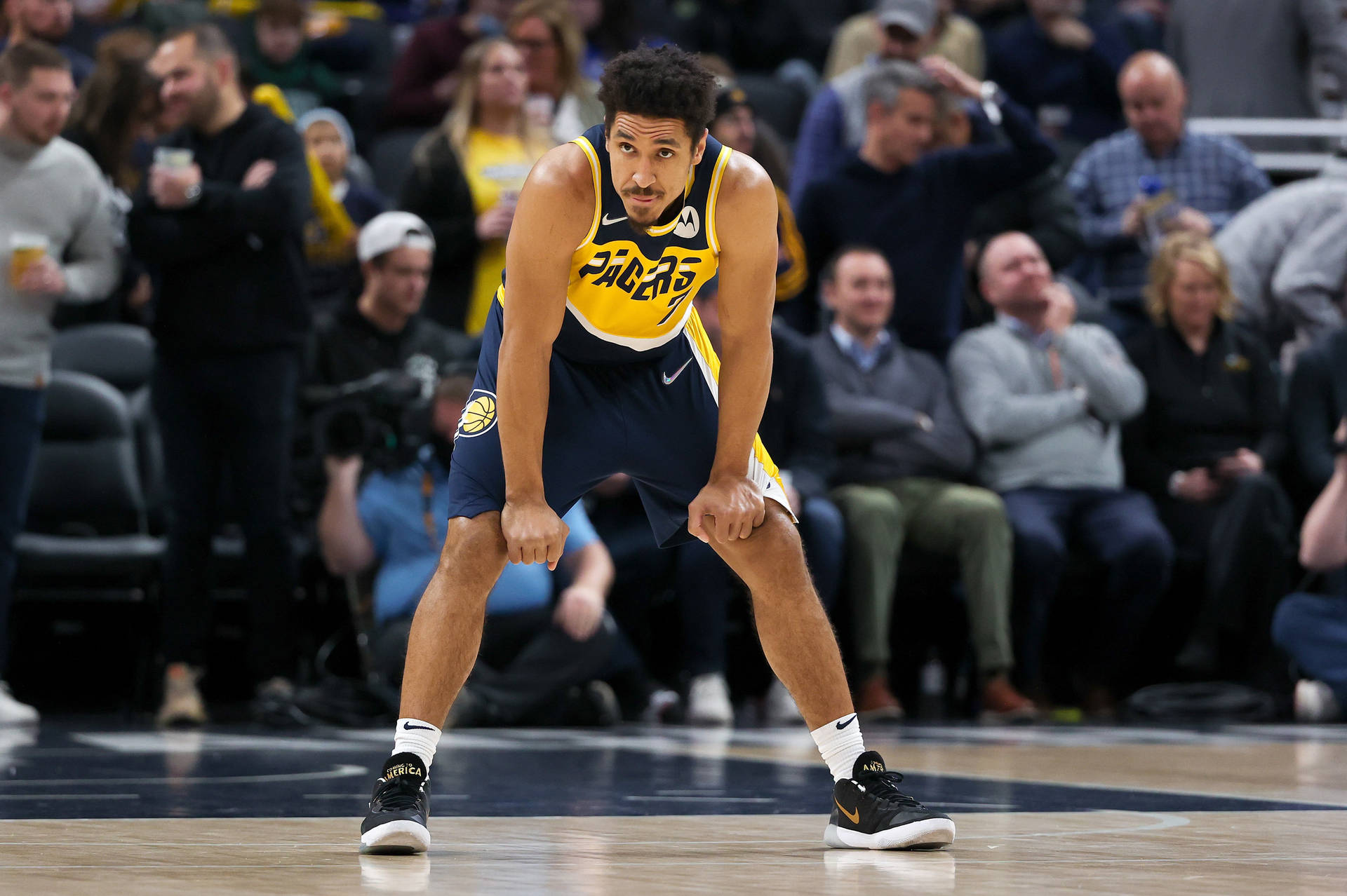 身穿Pacers球衣的籃球運動員在比賽中蹲在球場上。