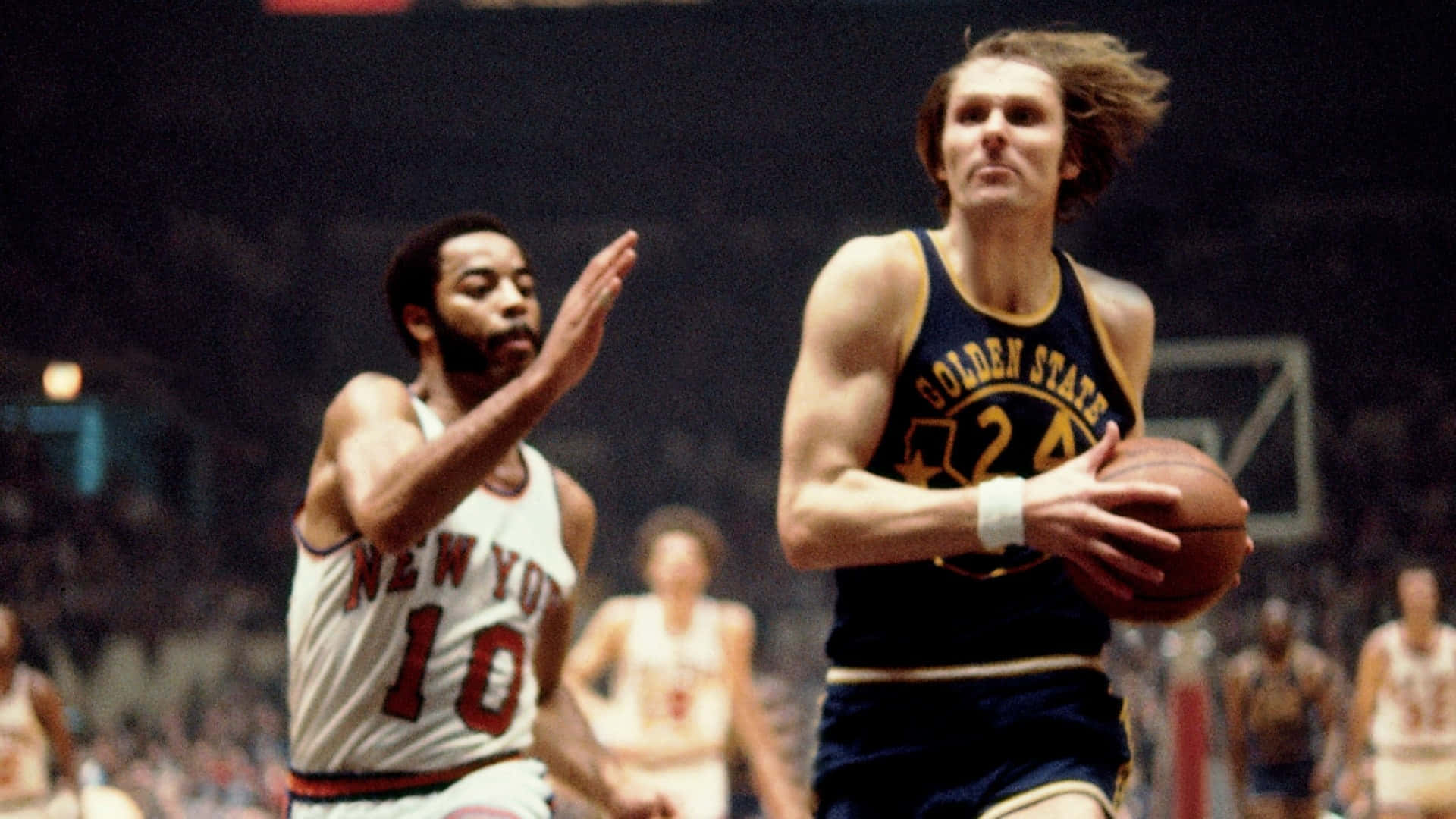 NBA瑞克·巴里與華特·弗雷澤 壁紙 — 一位身穿金州球衣的復古籃球運動員在擁擠的球場上運球，同時被紐約人隊球員防守。