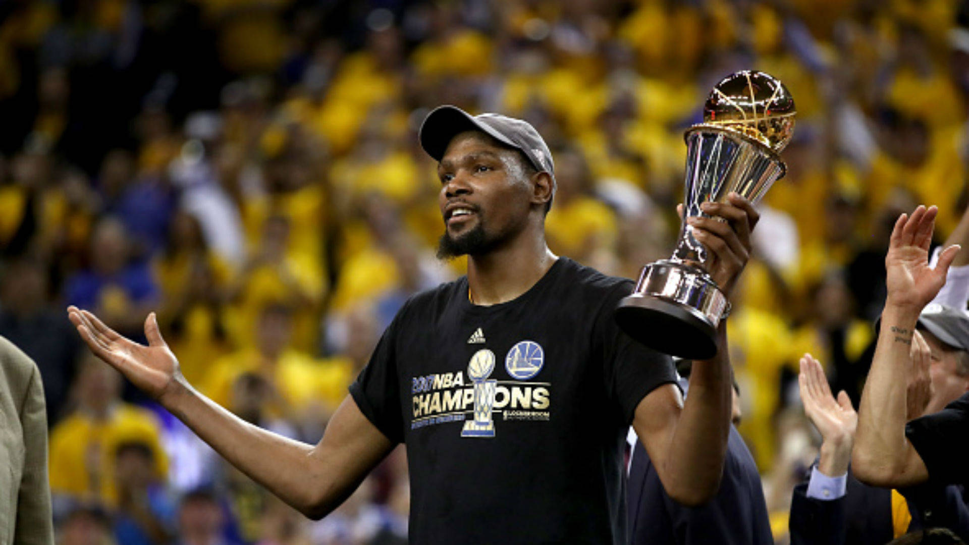 NBA總決賽MVP杜蘭特 壁紙 — 籃球運動員在身穿黃色衣服的喧鬧人群面前高舉NBA冠軍獎盃。