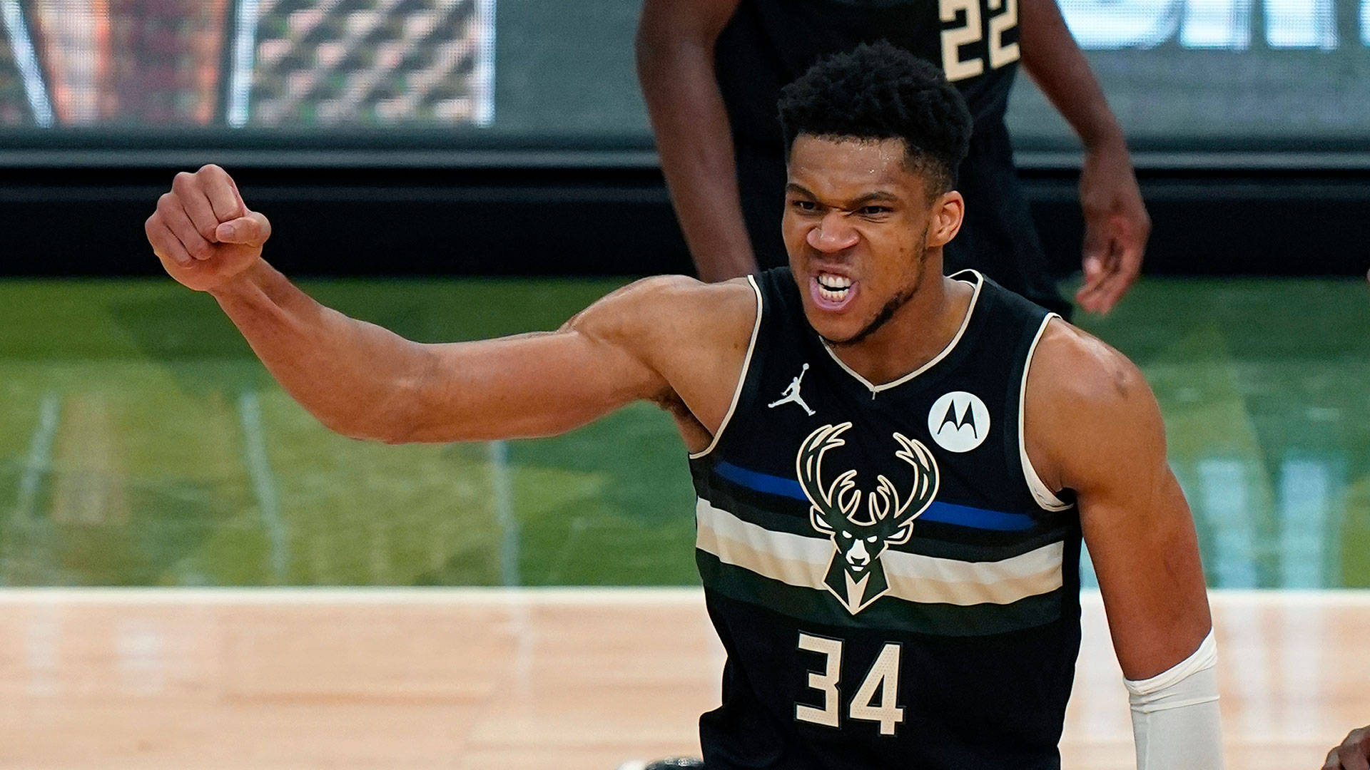 NBA總決賽密爾瓦基勝利 壁紙 — 一名身穿密爾沃基公鹿隊球衣的籃球運動員在光滑的球場上緊握拳頭，神情專注。