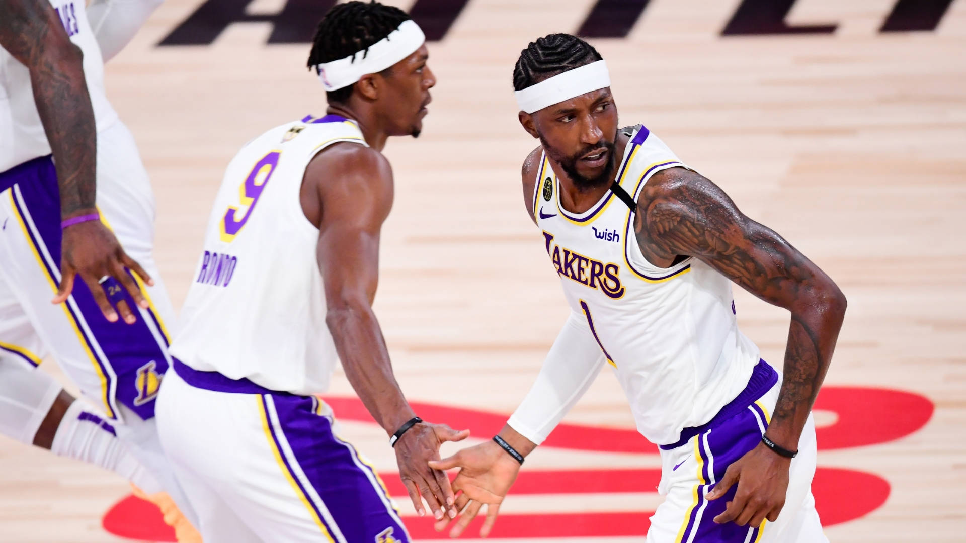 NBA總決賽強勁湖人隊 壁紙 — 兩名身穿白色和紫色球衣的湖人籃球運動員在拋光木地板上進行比賽時激烈溝通。