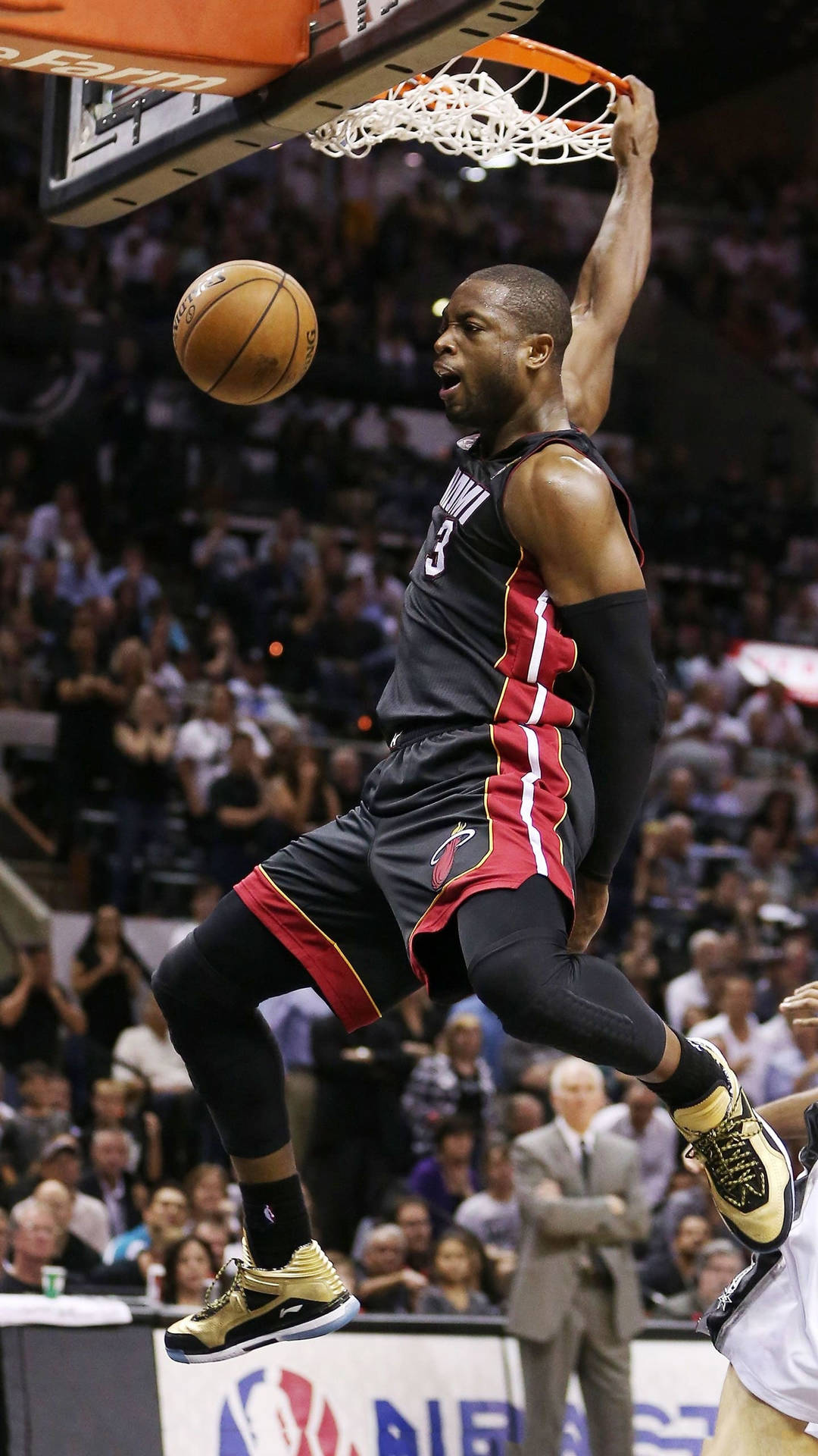 NBA總決賽德懷恩·韋德經典灌籃瞬間 壁紙 — 一位身穿黑紅色球衣的籃球運動員在擠滿觀眾的體育館比賽中，專注地灌籃。