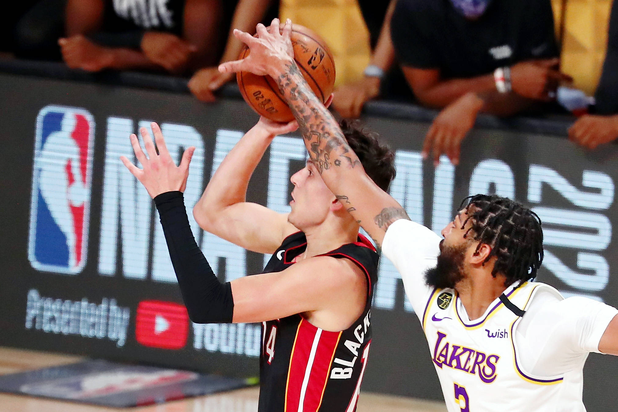 NBA總決賽湖人隊奪冠 壁紙 — 一名身穿黑紅色球衣的籃球運動員正在跳投，而一名身穿白色湖人球衣的防守球員試圖封阻該投籃。