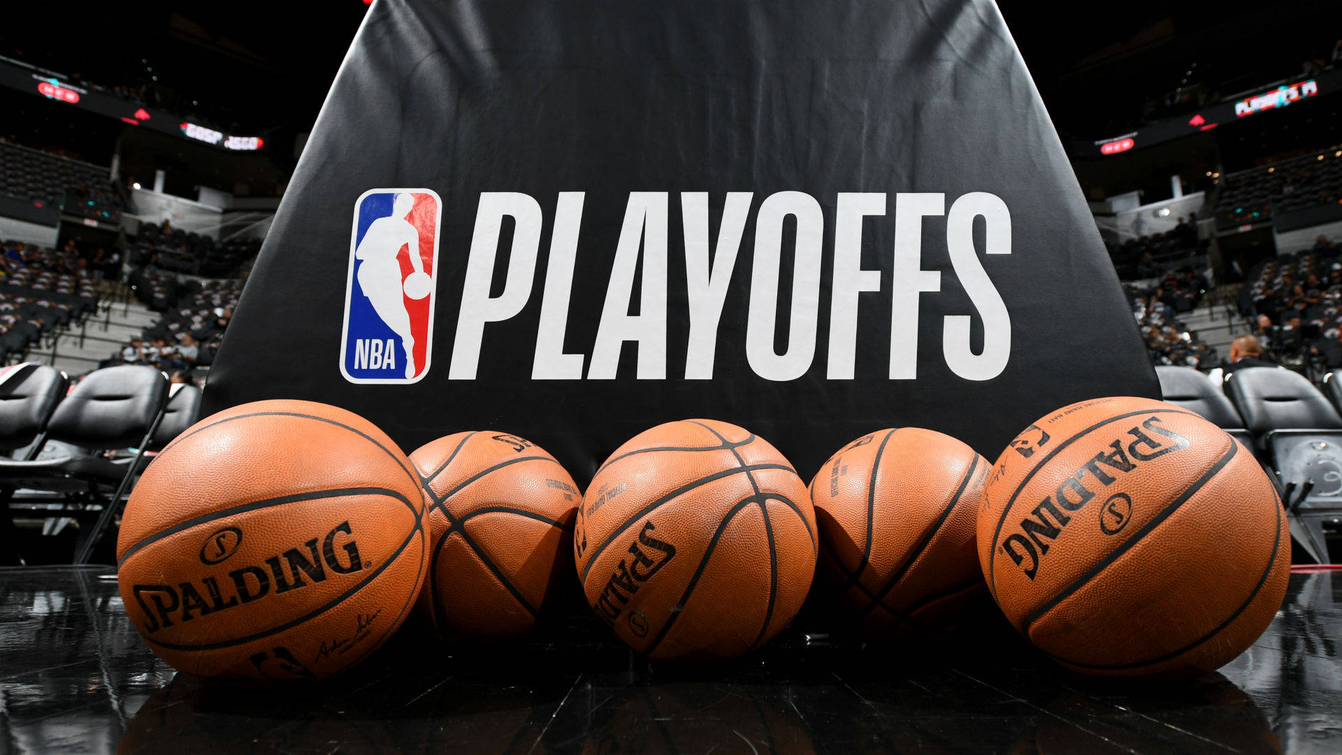 NBA總決賽激戰瞬間 壁紙 — 五個 Spalding 籃球放在一個昏暗的體育館內，空座位前掛著黑色 NBA 季後賽橫幅。