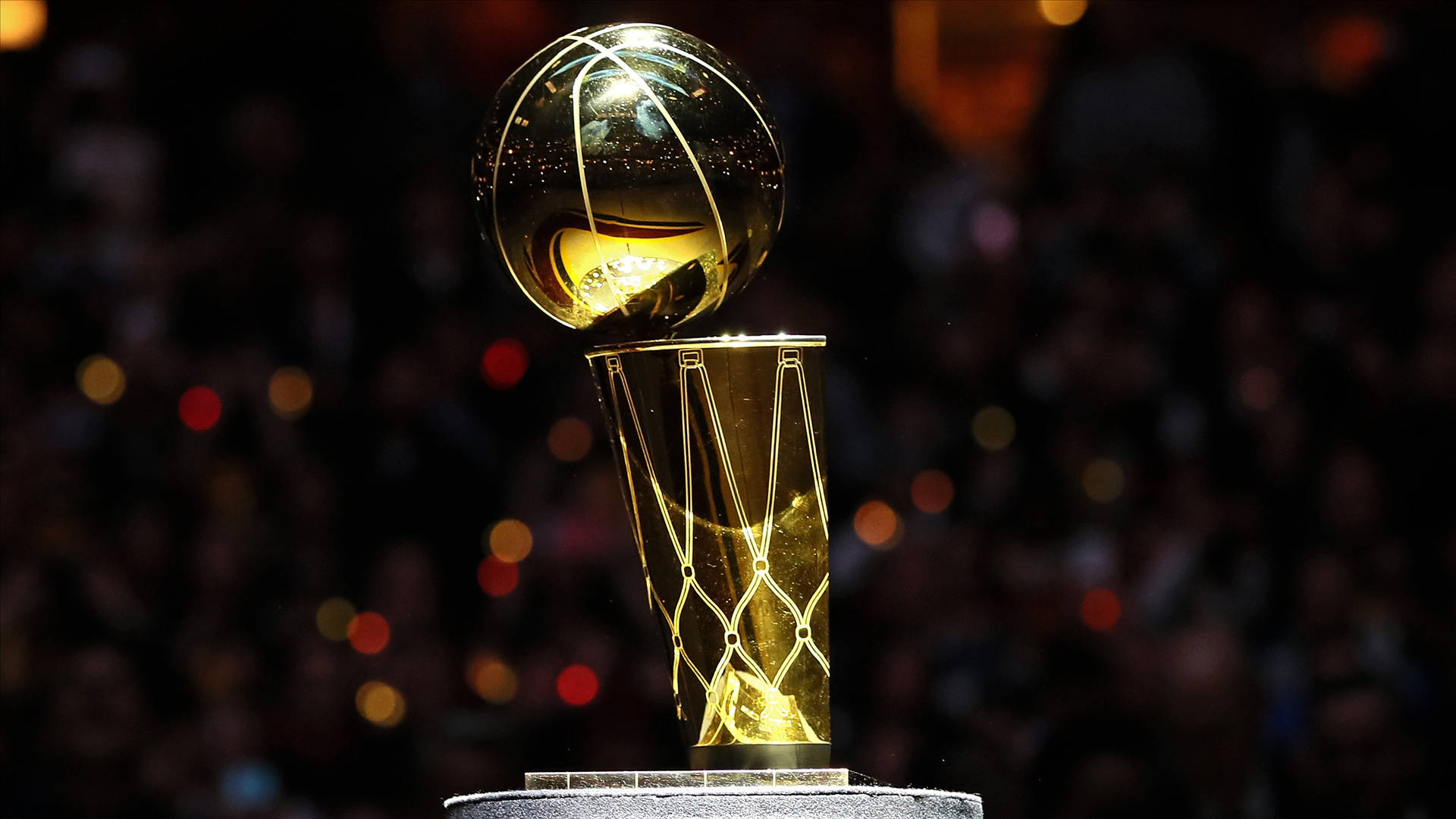 NBA總決賽經典金獎盃 壁紙 — 金色NBA冠軍獎盃在聚光燈下閃耀，背景是模糊的人群。