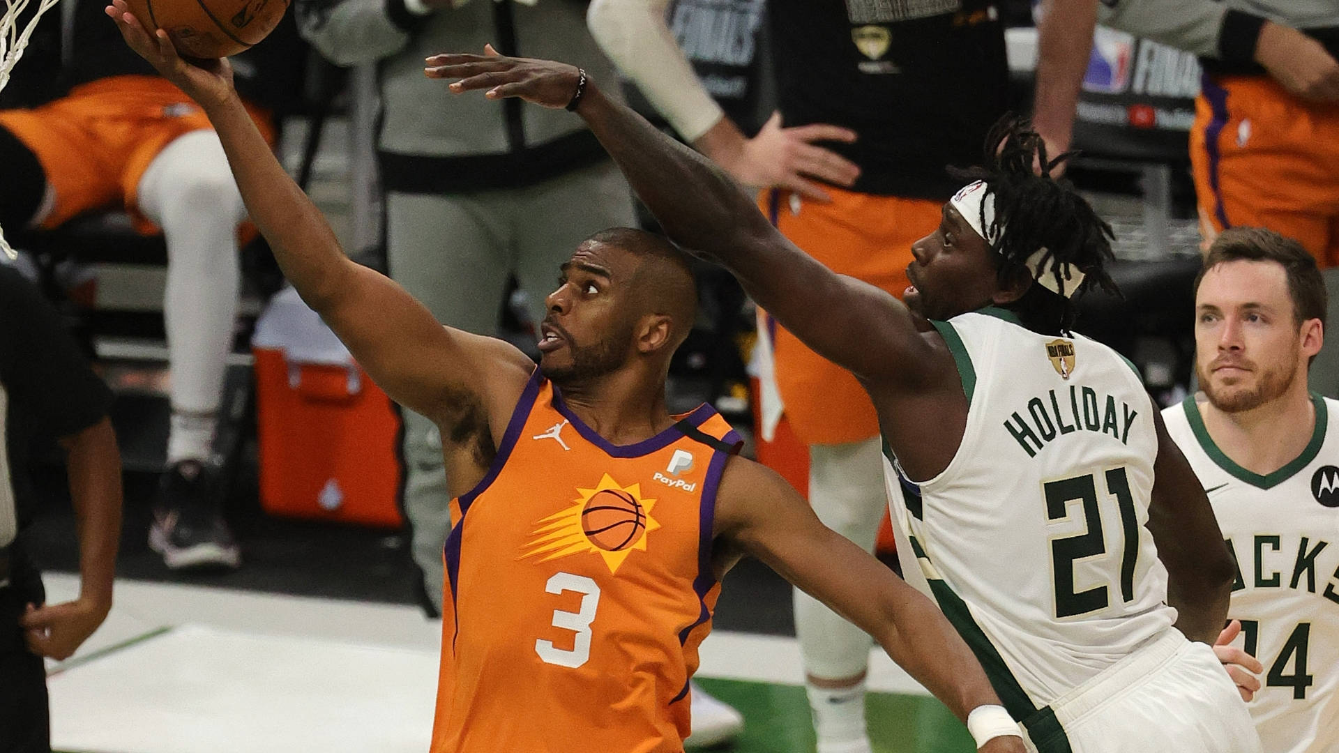 NBA總決賽霍利迪暴力封蓋 壁紙 — 一名身穿橙色球衣的籃球運動員在比賽中投籃，同時被一名身穿白色球衣的球員防守。