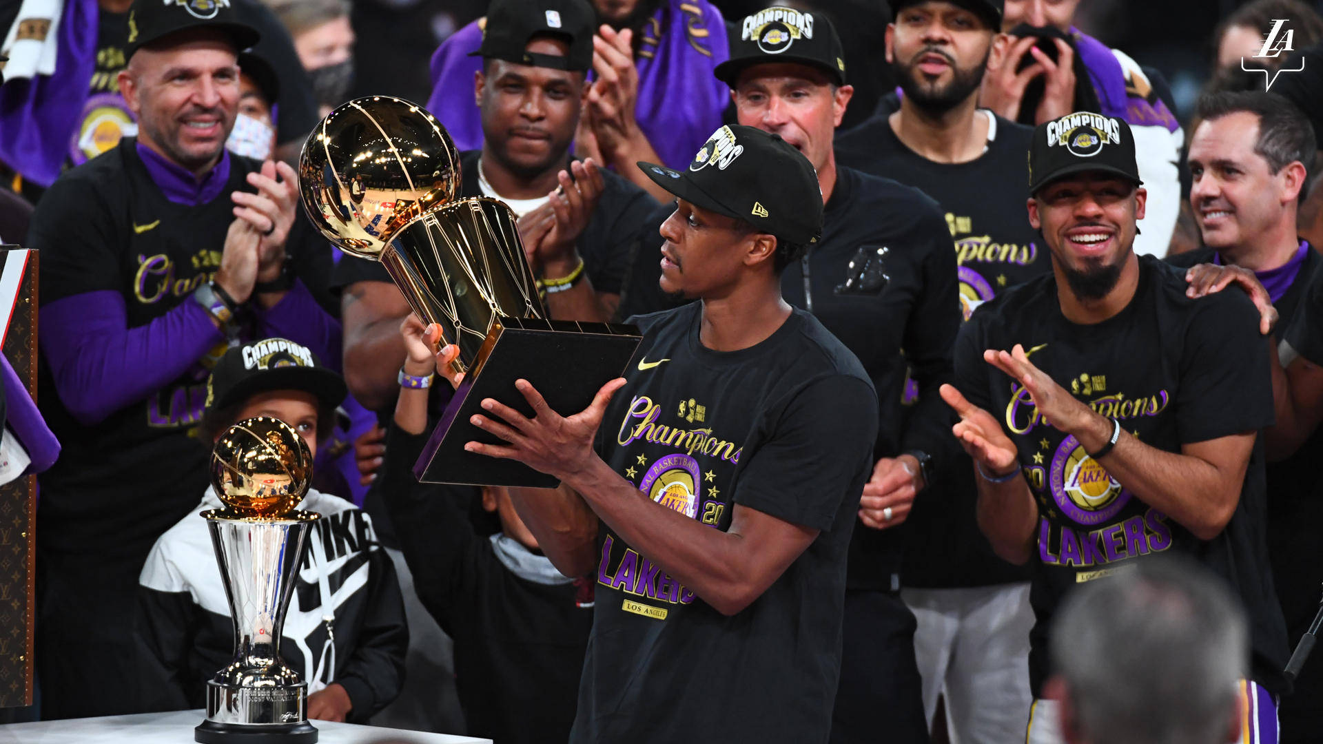 NBA總決賽頒獎典禮 壁紙 — 一名籃球運動員自豪地高舉閃亮的NBA冠軍獎盃，身穿黑色和紫色的隊友在他周圍慶祝。