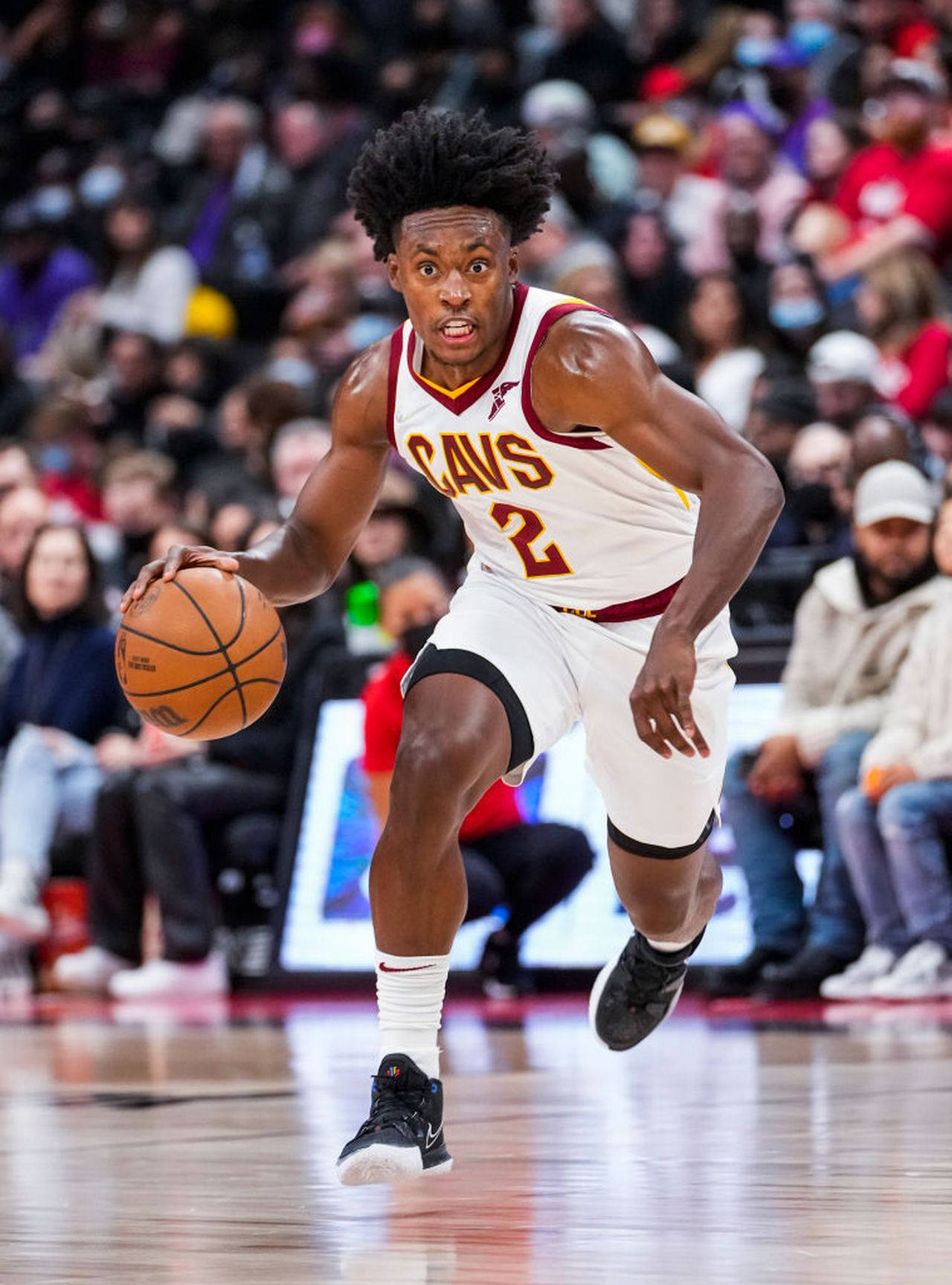 NBA聯賽科林·塞克森 壁紙 — 一名身穿騎士隊球衣的籃球運動員在比賽中激烈運球，背景是擠滿的人群。