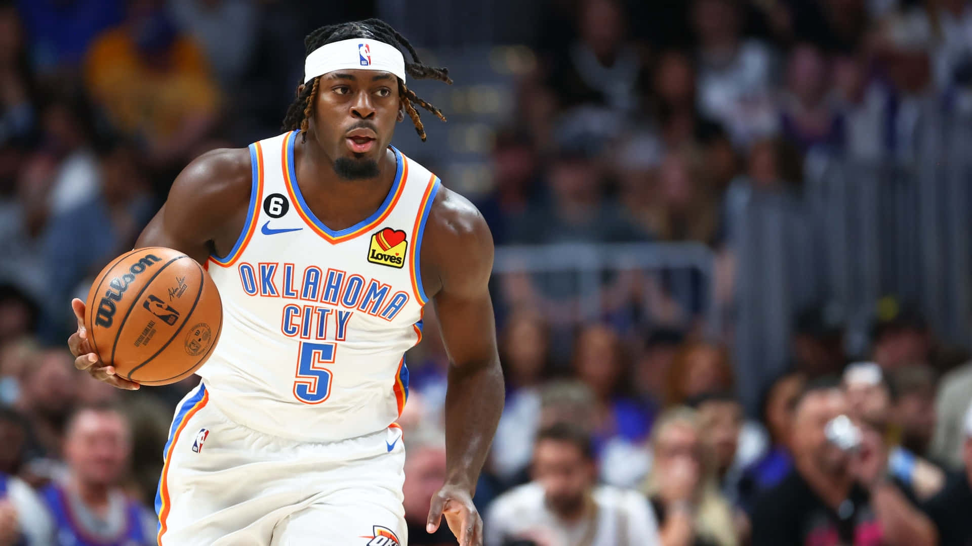 NBA雷霆隊盧根茲·多特身穿5號球衣 壁紙 — 一名身穿奧克拉荷馬城球衣的籃球運動員在比賽中激烈運球，背景是模糊的人群。